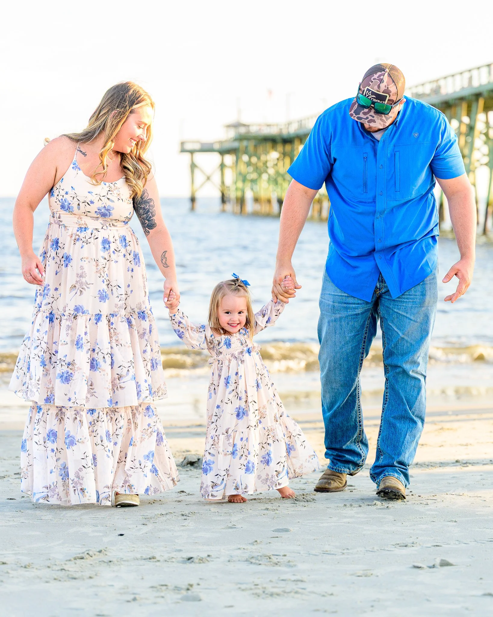 Family walking along the beach near Oak Island Pier during an evening family photo session on Oak Island, North Carolina.