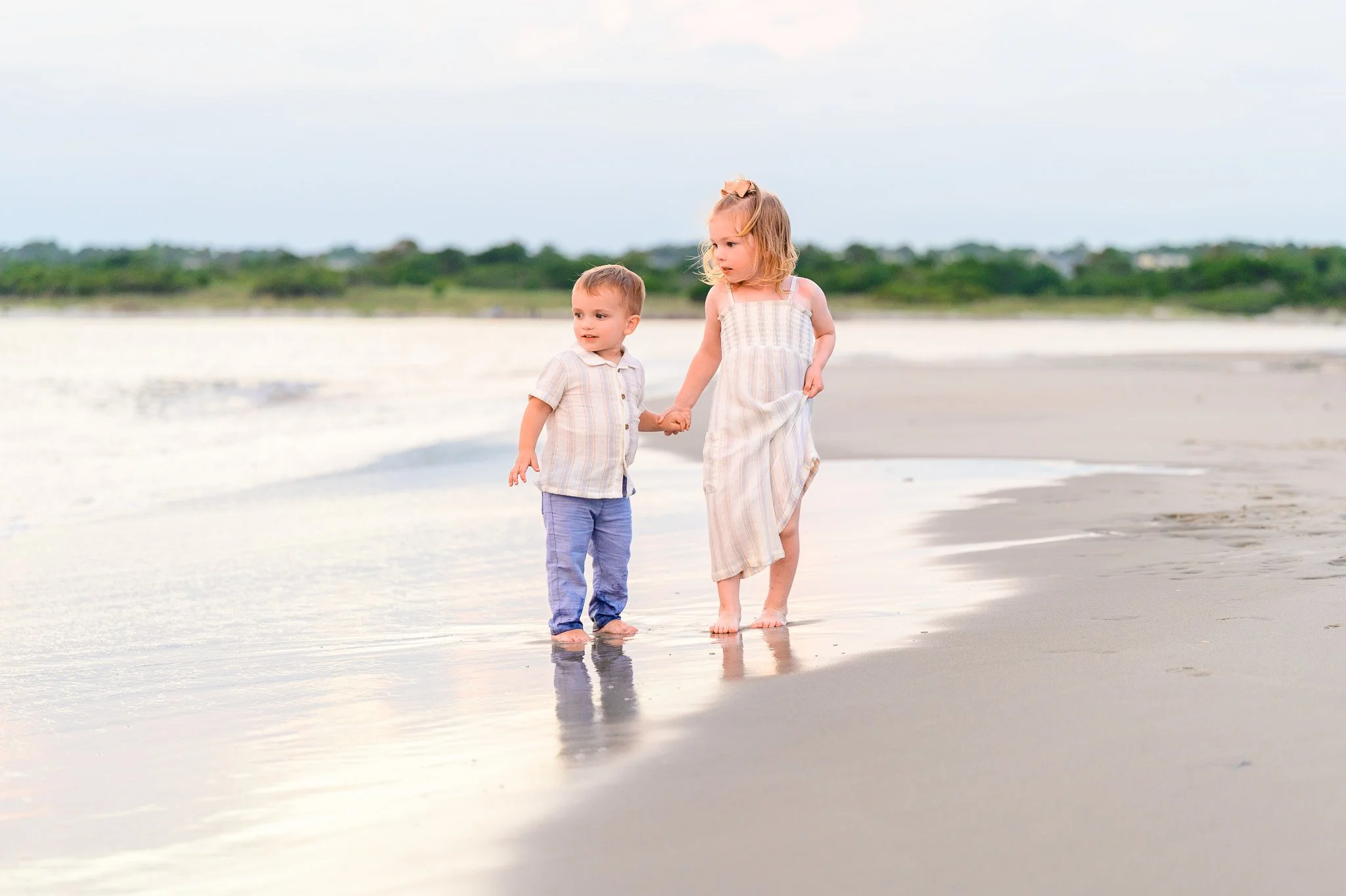 Young children walking along the shoreline at The Point on Oak Island, North Carolina during a family beach visit.