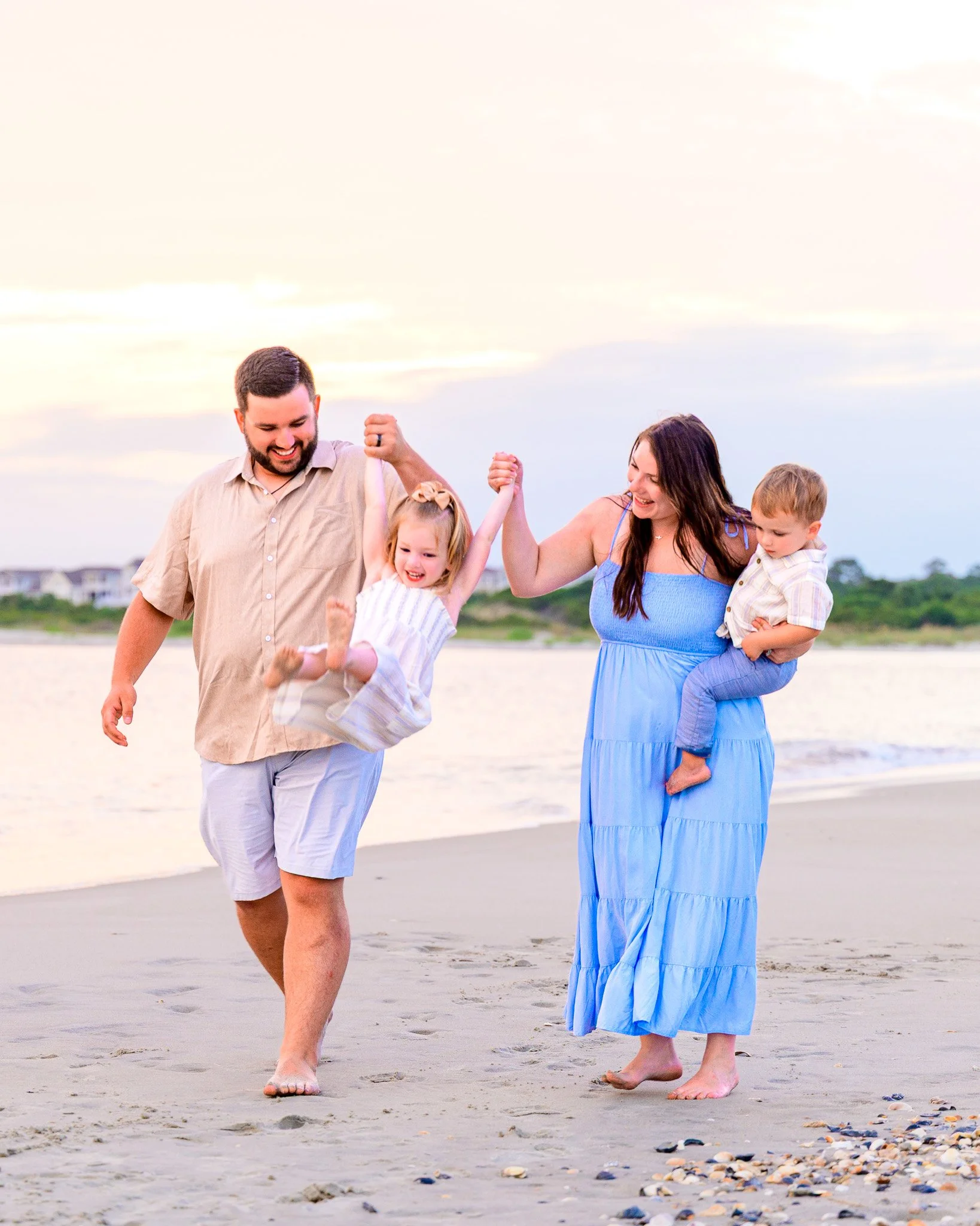 Family walking along the shoreline at The Point on Oak Island, North Carolina during a summer evening.
