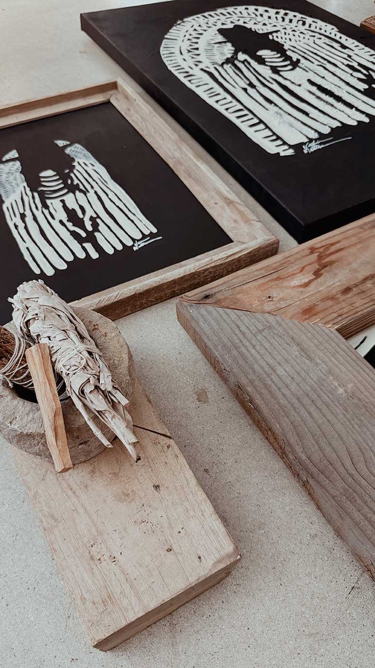 Two black-and-white animal-themed artwork prints on black background, one framed with wooden borders and the other unframed, displayed on a light-colored surface with pieces of wood and a woven decorative item nearby.