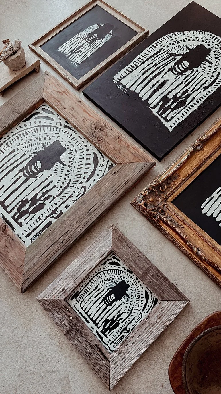 Multiple framed artworks on floor, featuring black and bone paintings in different frames and styles, with some vintage ornate frames and hand-made wooden frames.