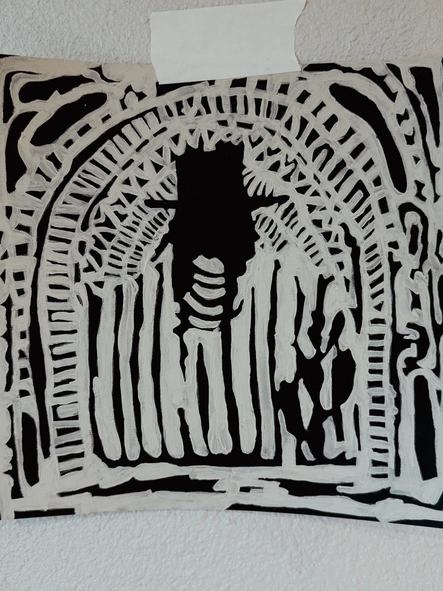 Black paper with white abstract drawn lines forming a face with long hair and a background of geometric patterns, taped to a wall.