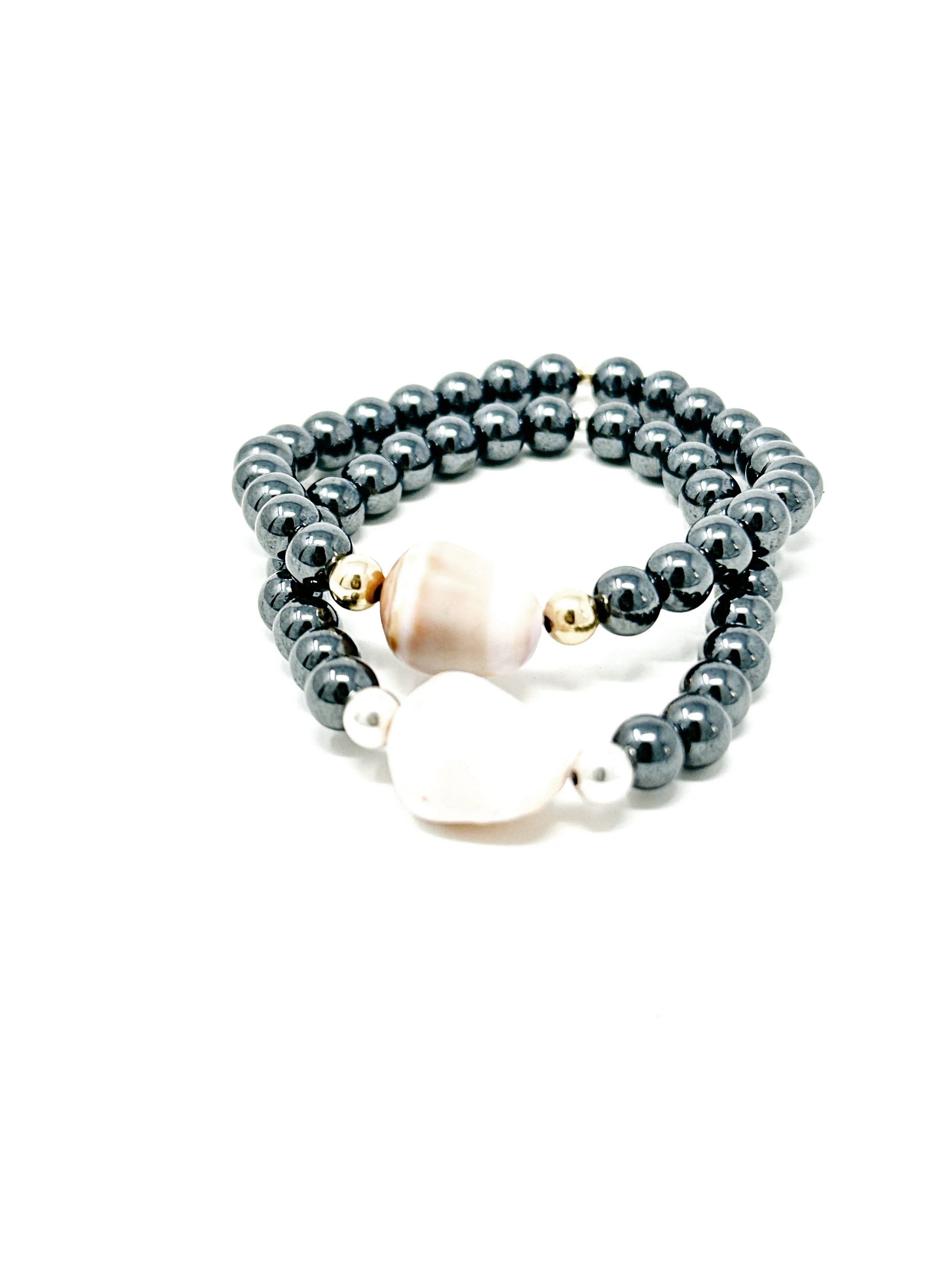 Ocean-inspired cone shell bracelet with natural hematite beads. Stretchy beaded design with earthy tones and modern minimalist style.