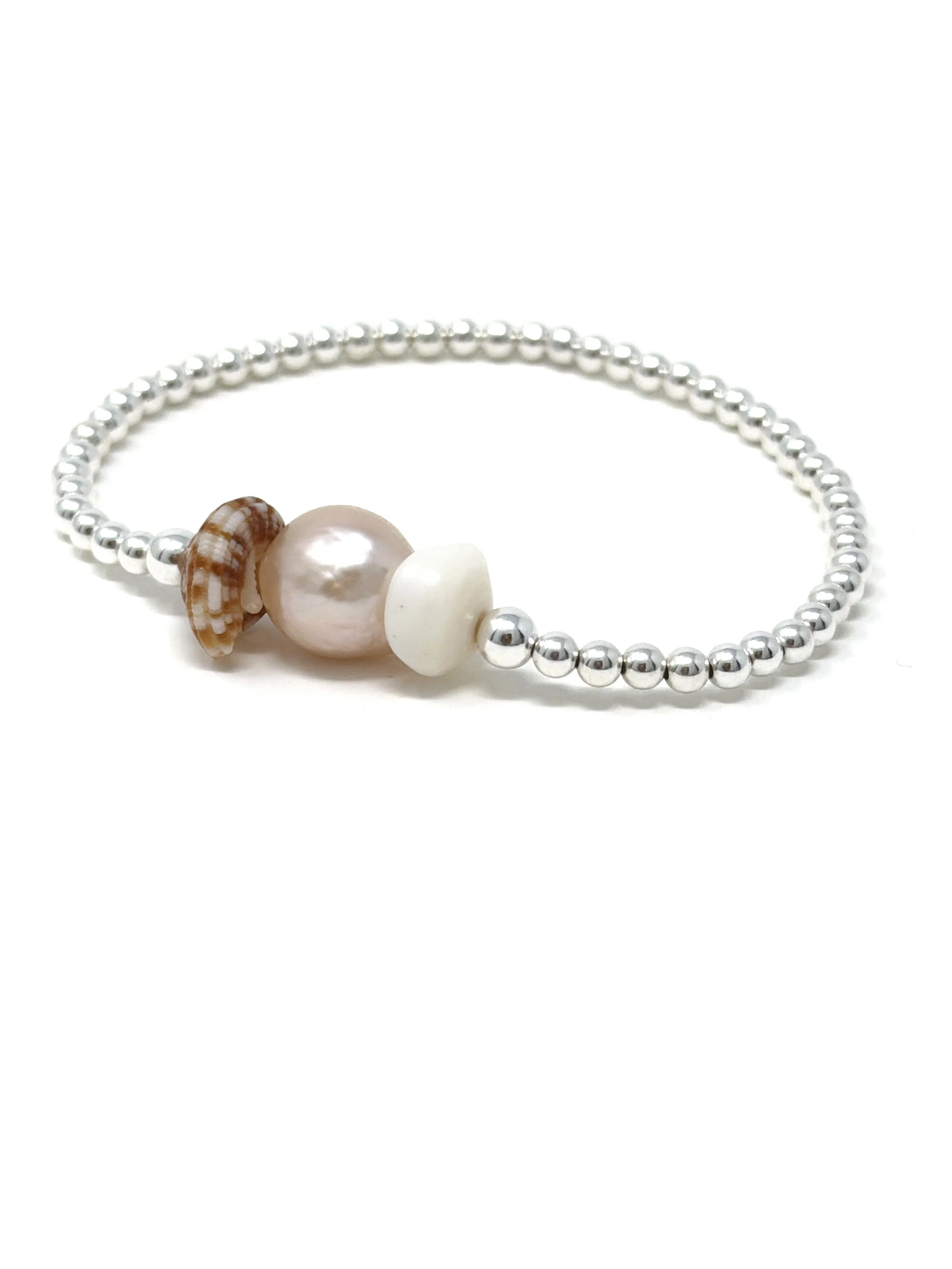Handmade pearl and shell bracelet featuring a pink Edison pearl with puka or sun dial shells. Stretchy, ocean-inspired jewelry perfect for layering or everyday wear.