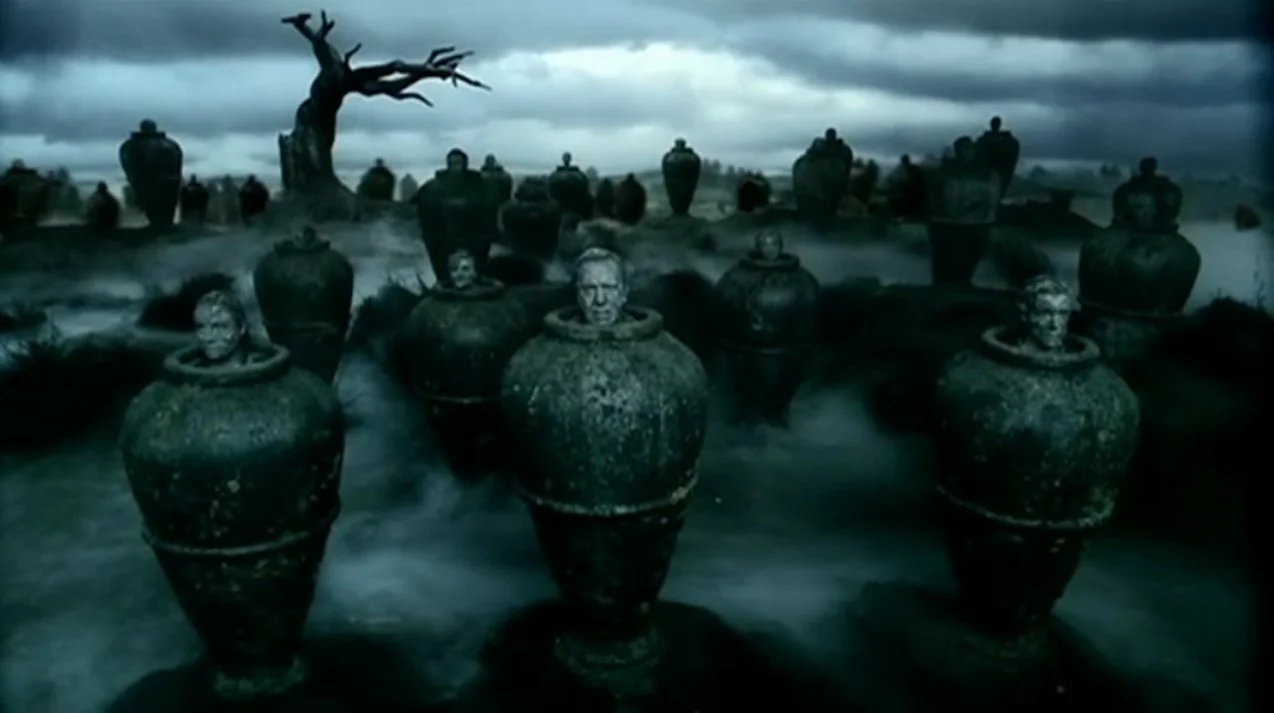 Dark and eerie landscape with a large, leafless tree and numerous ancient clay pots with human skulls inside, set against a stormy sky.