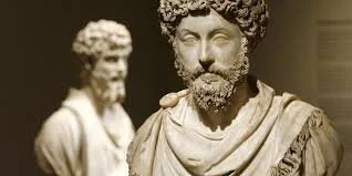 Two marble bust sculptures of ancient Roman men, with one in the foreground and the other in the background.