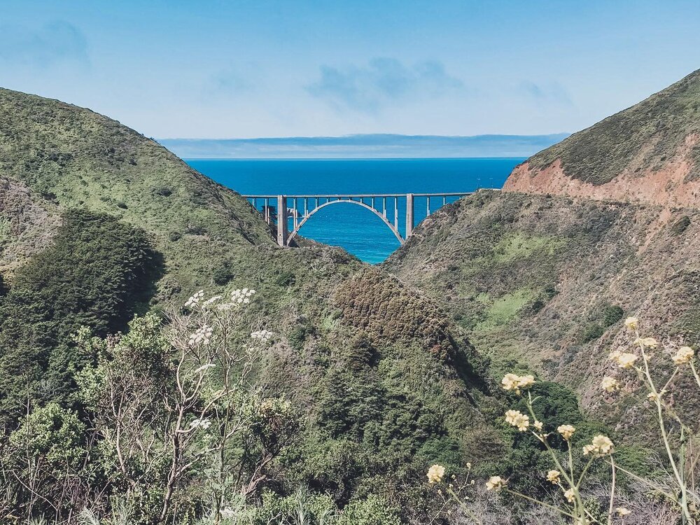 Anyone that has driven the PCH has definitely stopped to get a photo of the Bixby Bridge.

Most people get a shot of the bridge standing on the cliffside looking back at it, but the shot you really want is with the gorgeous Pacific Ocean behind it!

