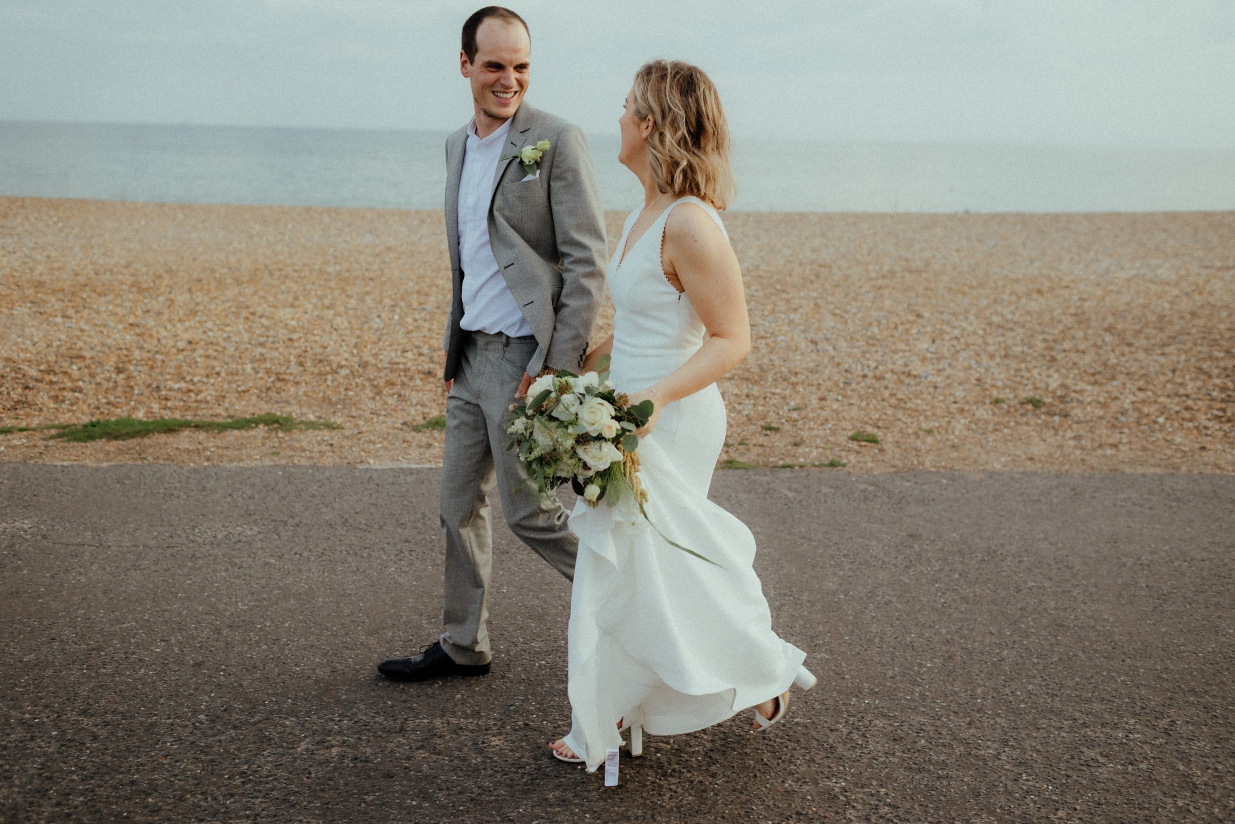 Wedding couple walk along Brighton Beach