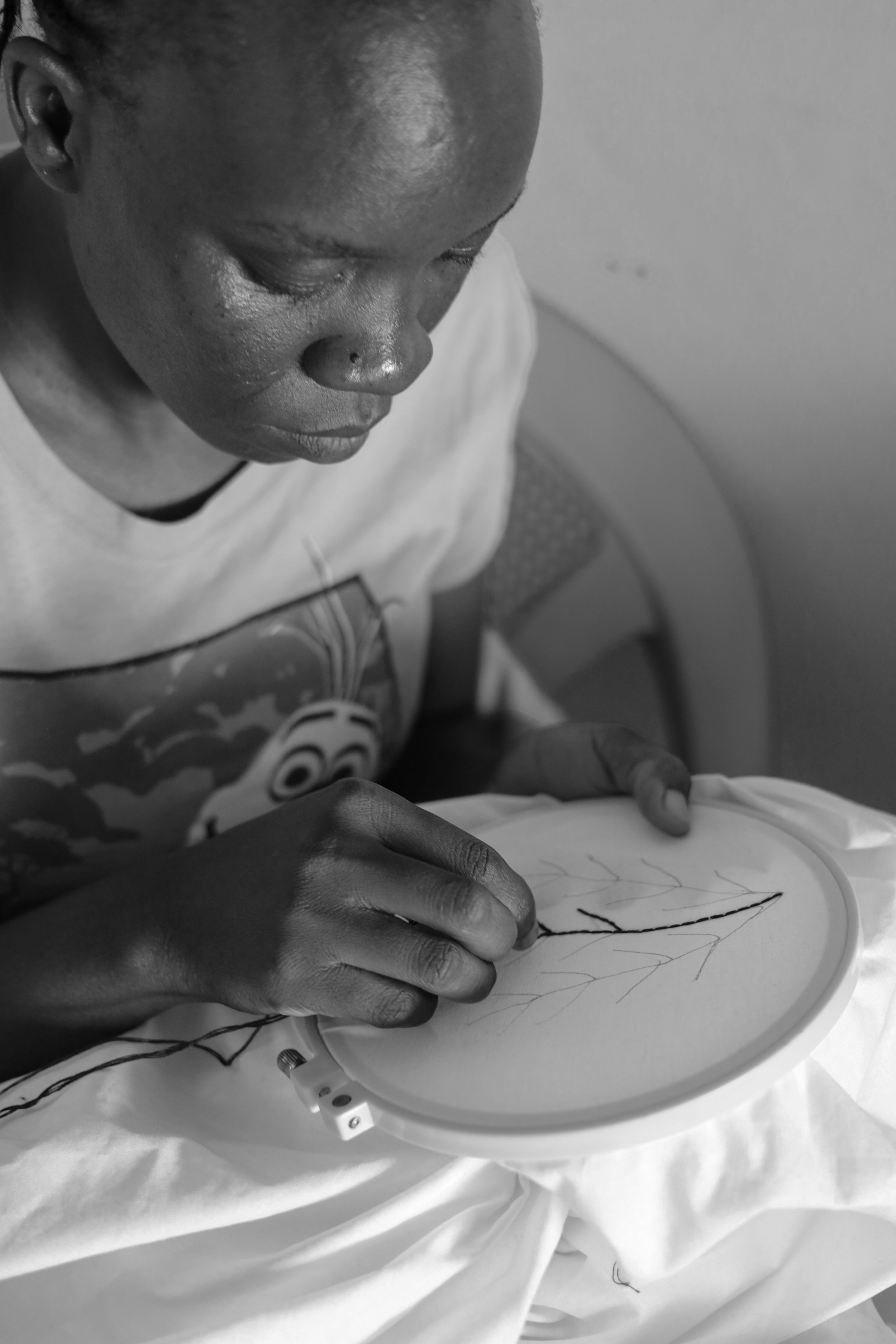 A person is embroidery on a fabric with a needle and thread, focusing on creating a design.