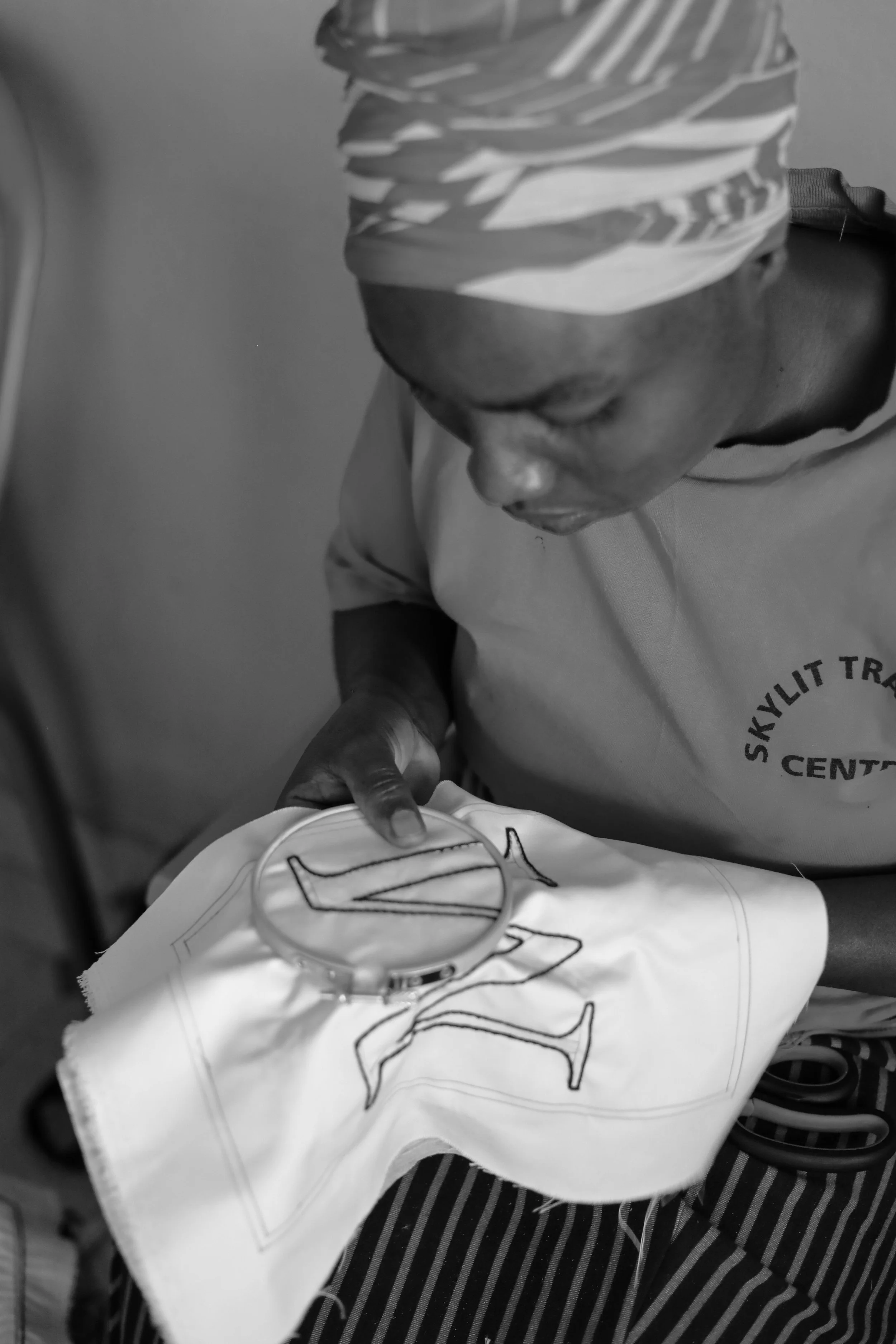 A person wearing a headscarf and a shirt embroidered with 'Skylyt Tr...'