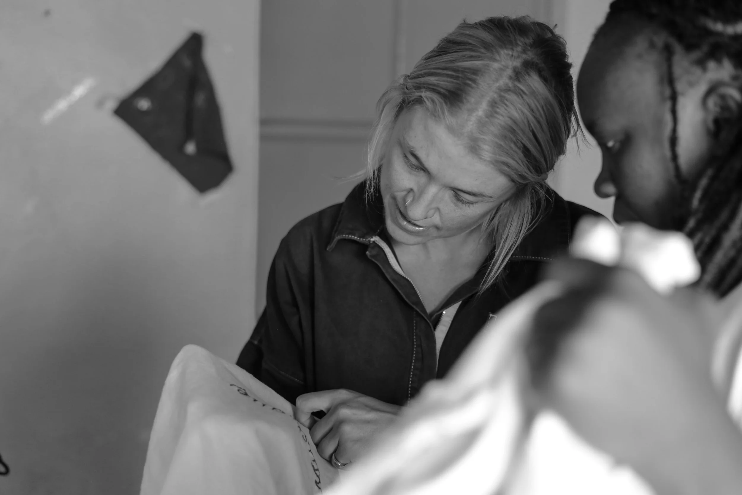 Two women reading or examining a paper together indoors, black and white