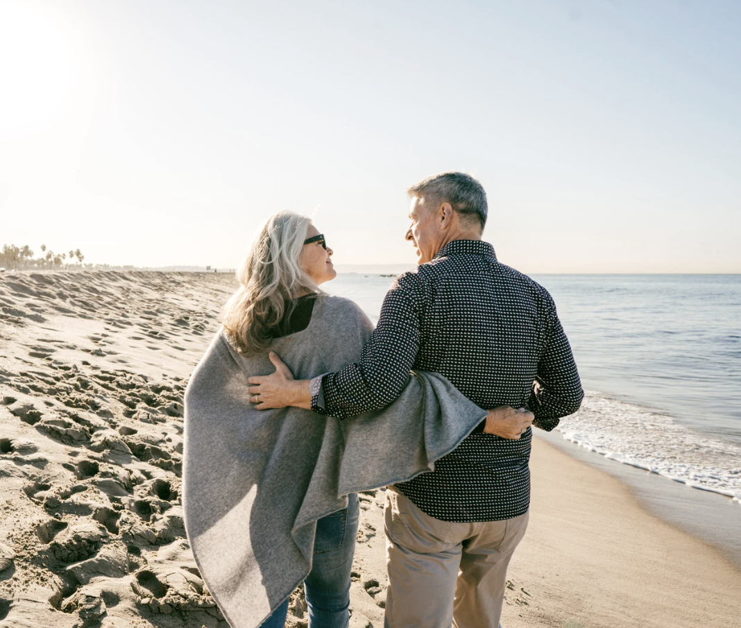 Couple walking along the beach with their arms around each other