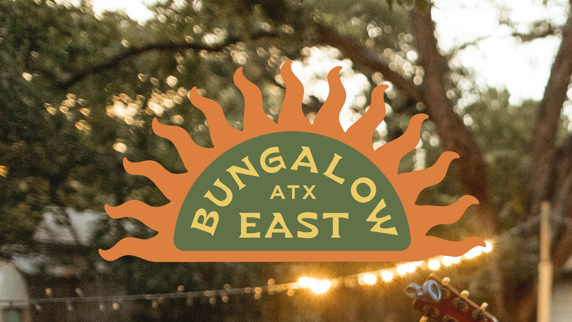 A sign with a sun design that reads "Bungalow at East" with a blurred outdoor background.