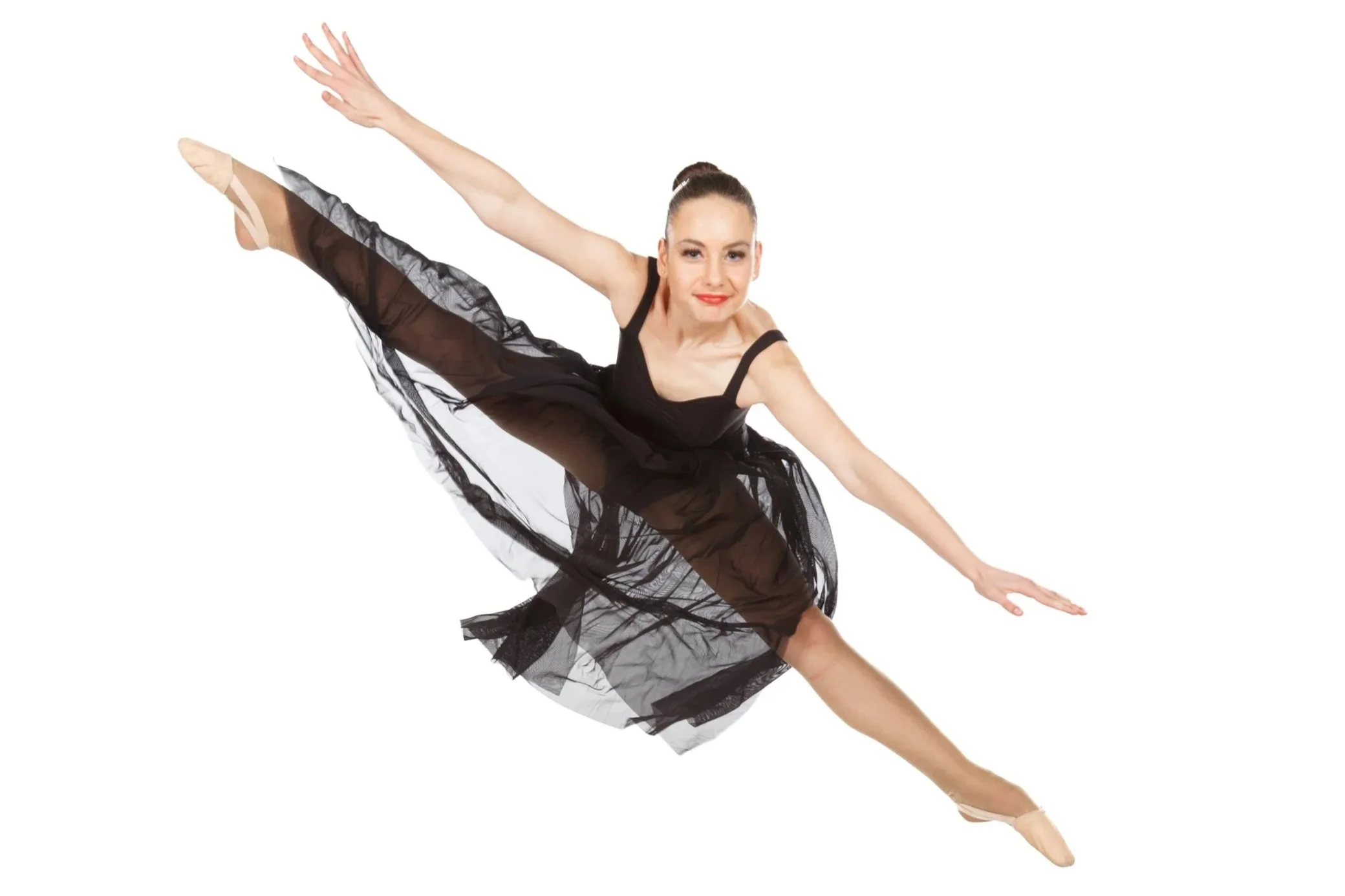 A dancer dressed in a black ballet dress performs a dance leap against a white background.