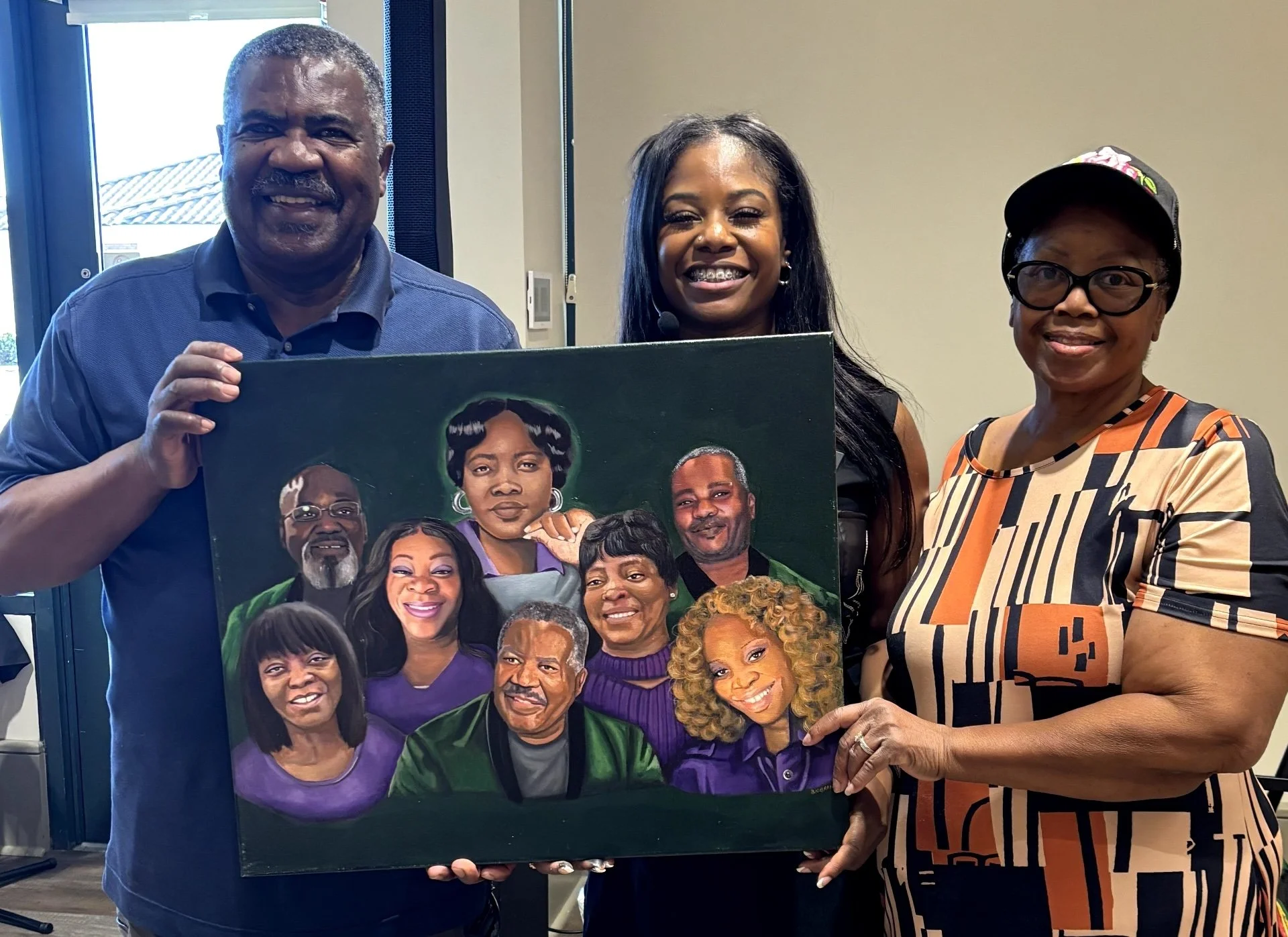 Three people standing inside holding a colorful portrait of nine individuals, with two women on the right and a man on the left, all smiling.