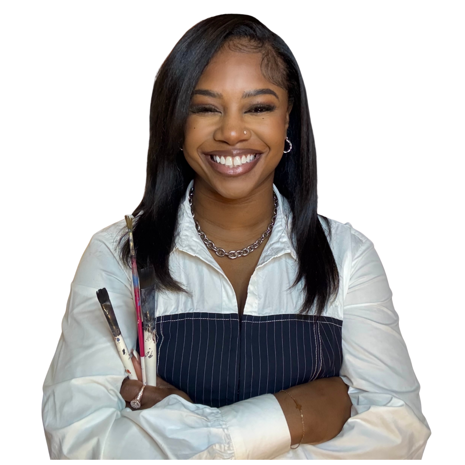 image of a woman smiling holding paint brushes with her arms crossed. in a white and blue shirt with a silver chain necklace. she also has straight hair.