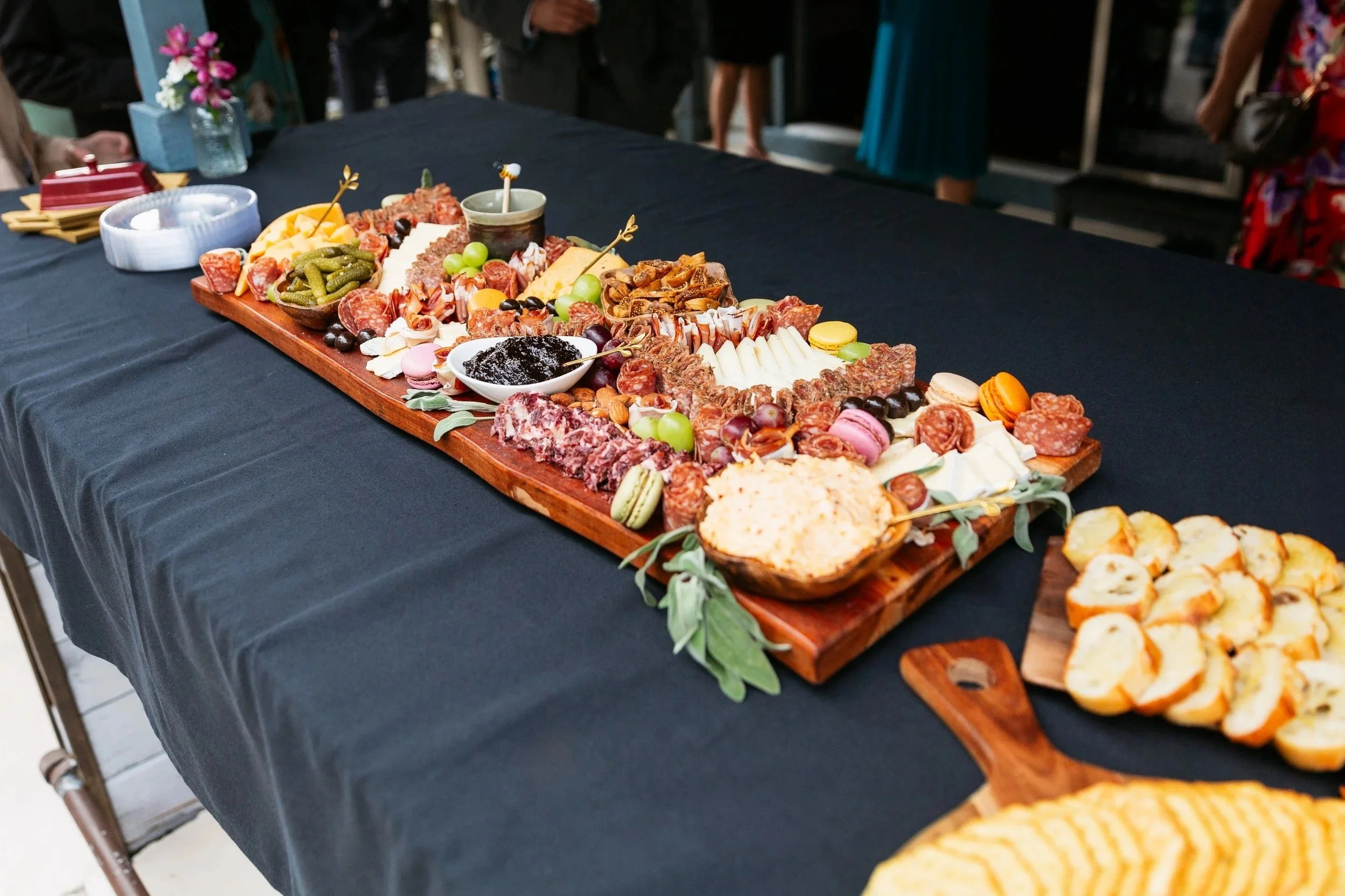 A charcuterie board for a micro wedding in St Augustine with an assortment of cheeses, meats, crackers, grapes, and spreadable toppings is displayed on a black tablecloth.