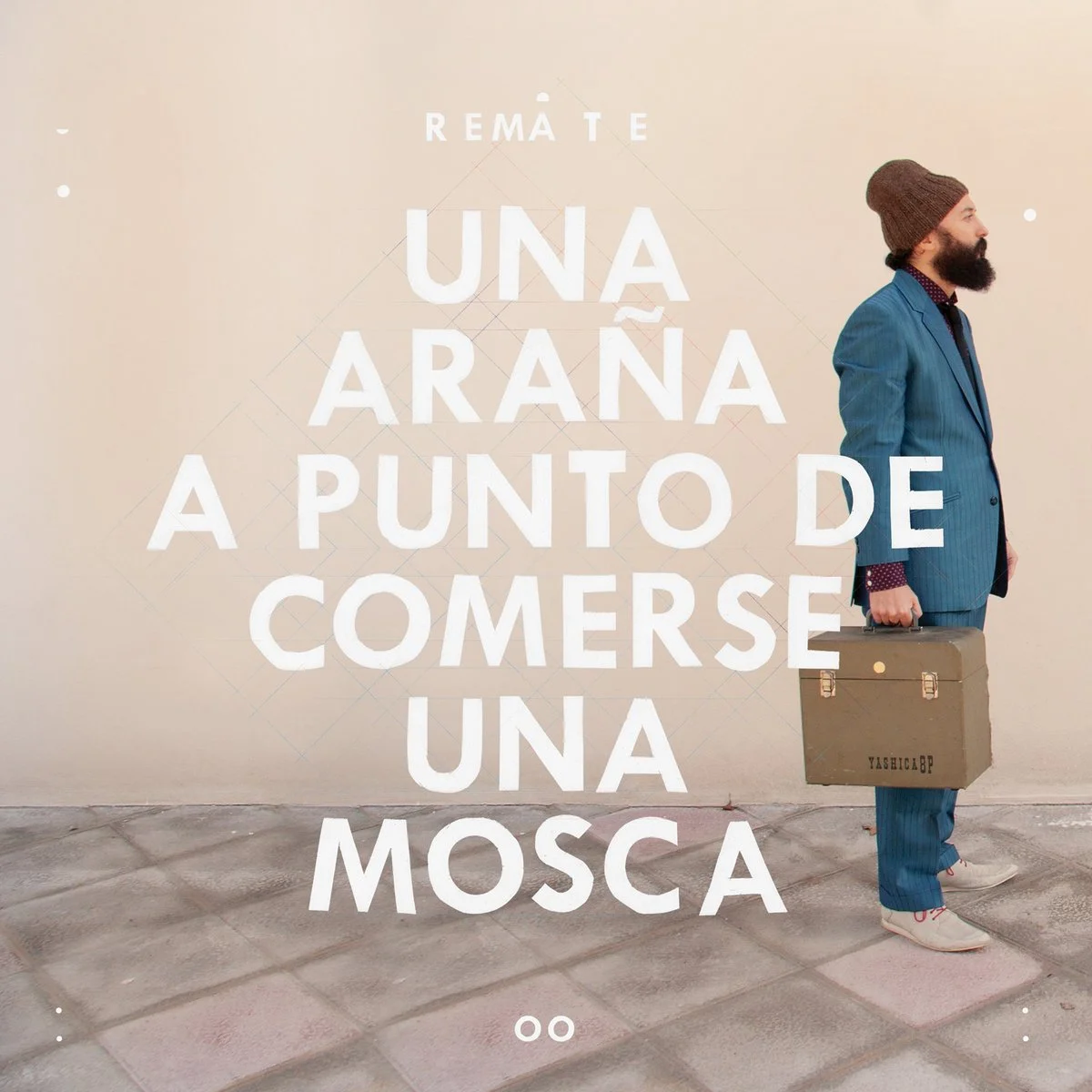 Portada del disco Una araña a punto de comerse una mosca de Remate. El músico posa com un traje azul brillante, un gorro y con un maletín antiguo en la mano frente a una pared vacía.