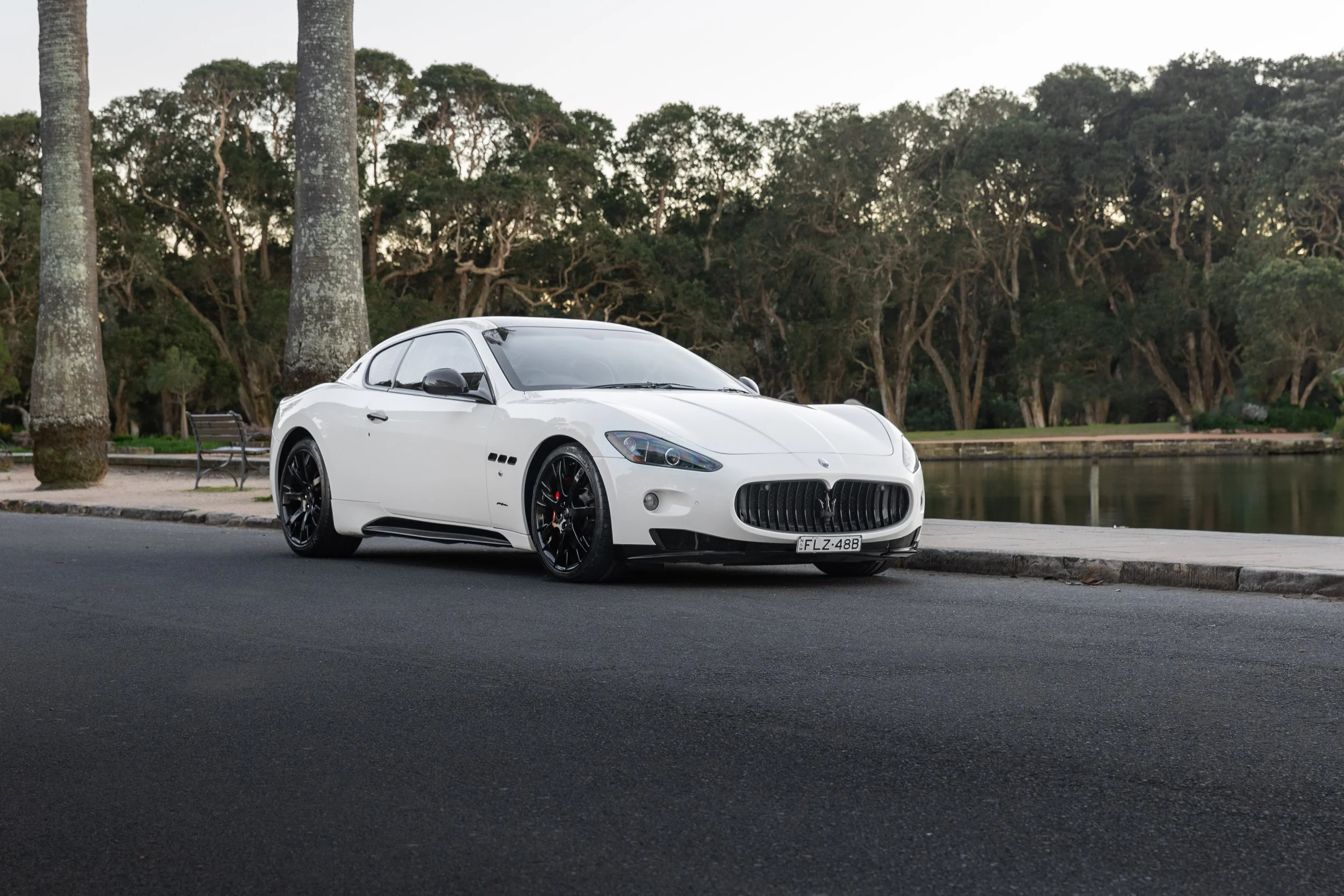 Maserati GranTurismo S straight-on front view, headlights lit, tree-lined Sydney avenue