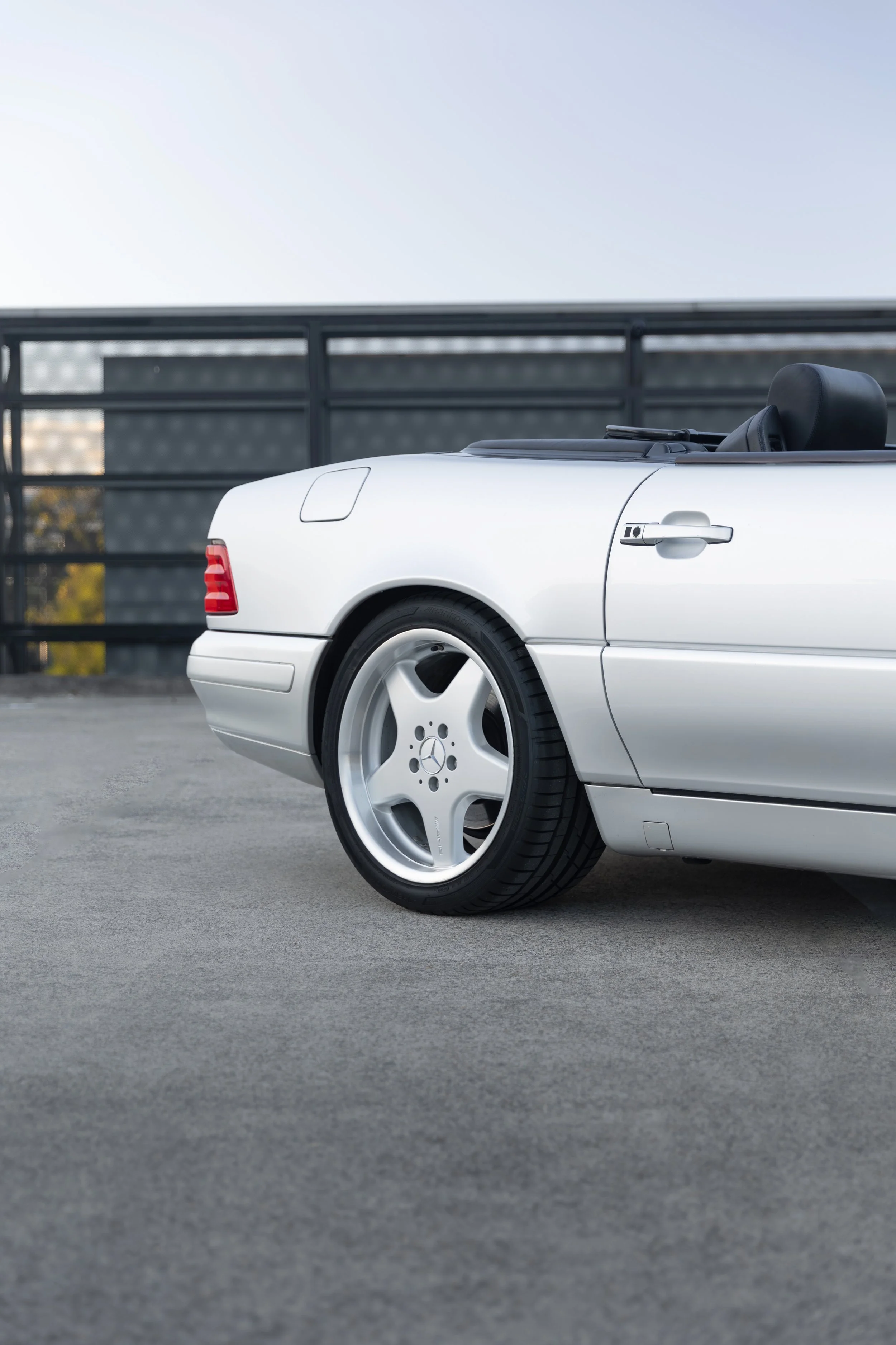 Side profile of a silver Mercedes-Benz SL 500 R129 showing its 18-inch AMG Monoblock wheels, Sydney.