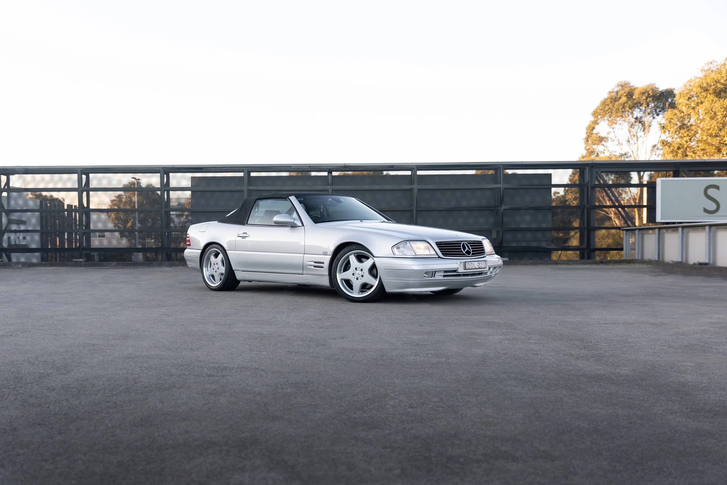 Silver Mercedes-Benz SL 500 R129 roadster side-on in warm afternoon light, Sydney rooftop.