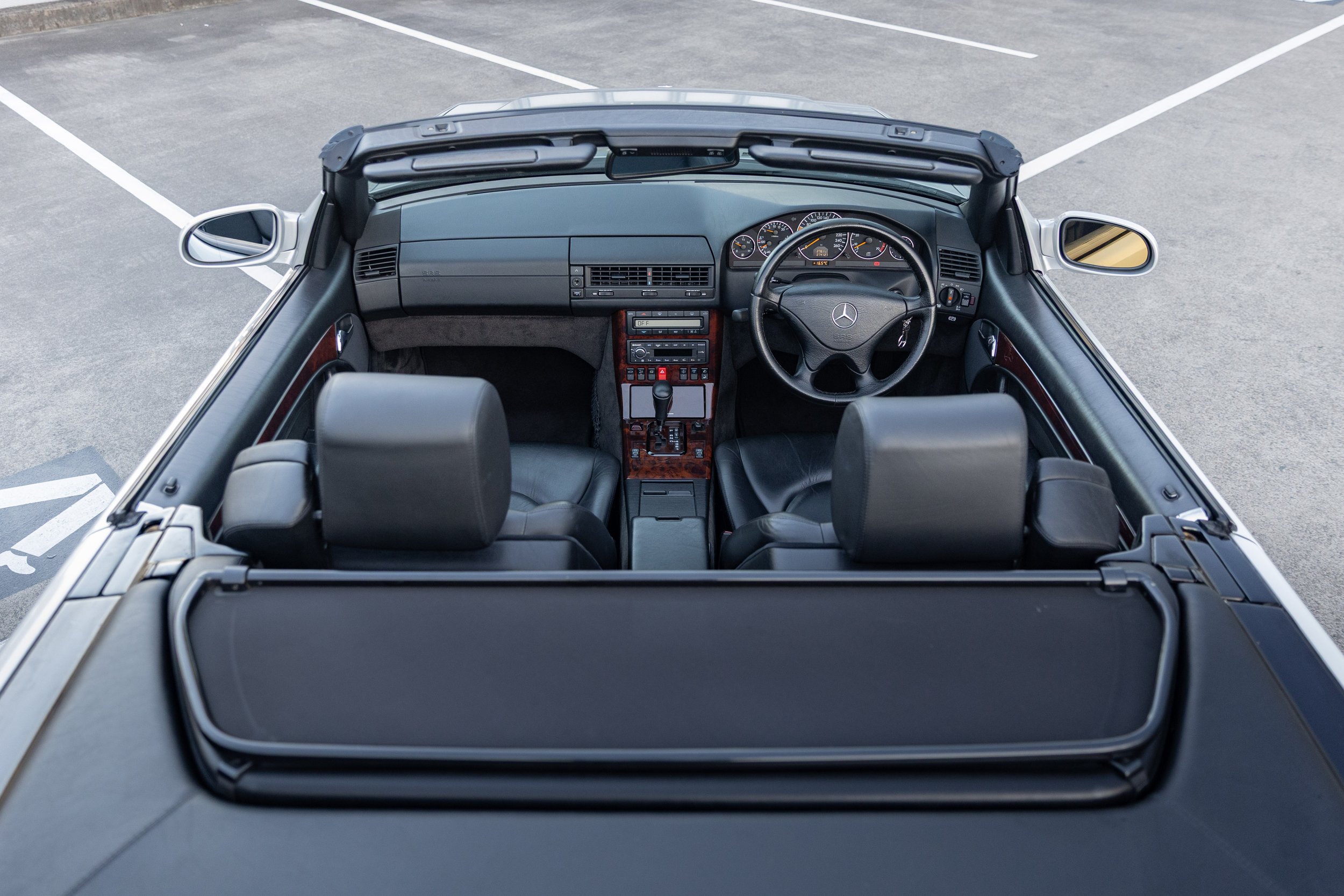 Top-down cabin view of a silver Mercedes-Benz SL 500 R129, black leather interior.