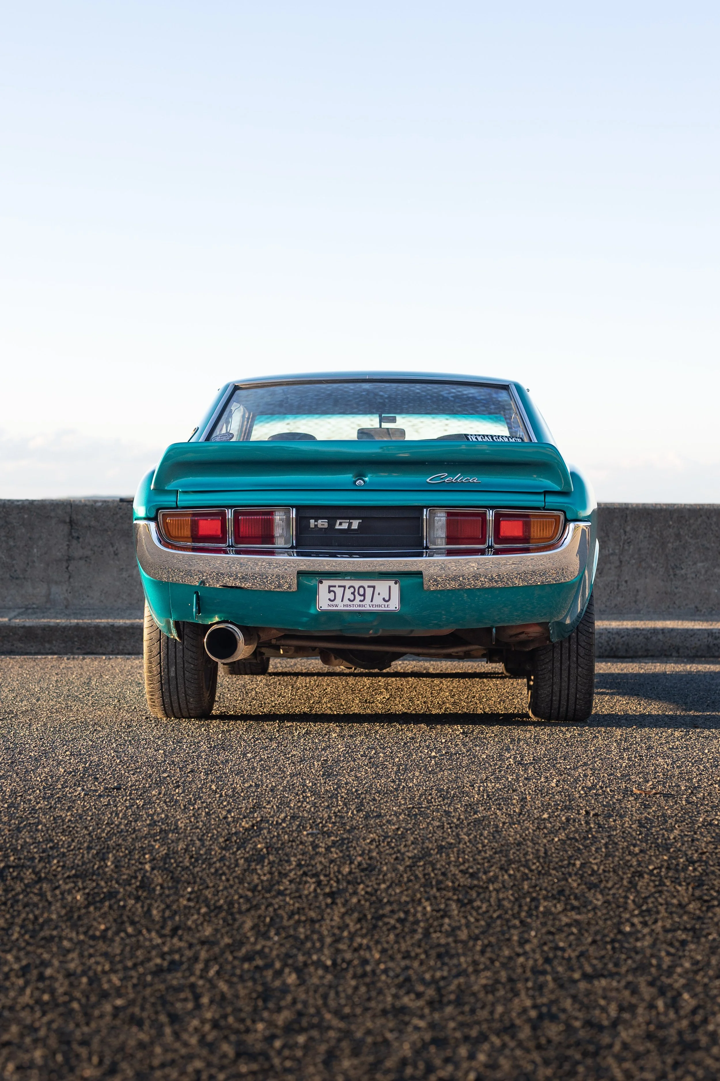 Rear view of a Toyota Celica TA22 1600GT with the "1.6 GT" badge, quad tail-lights and centre exhaust vintage Japanese coupe automotive photography.