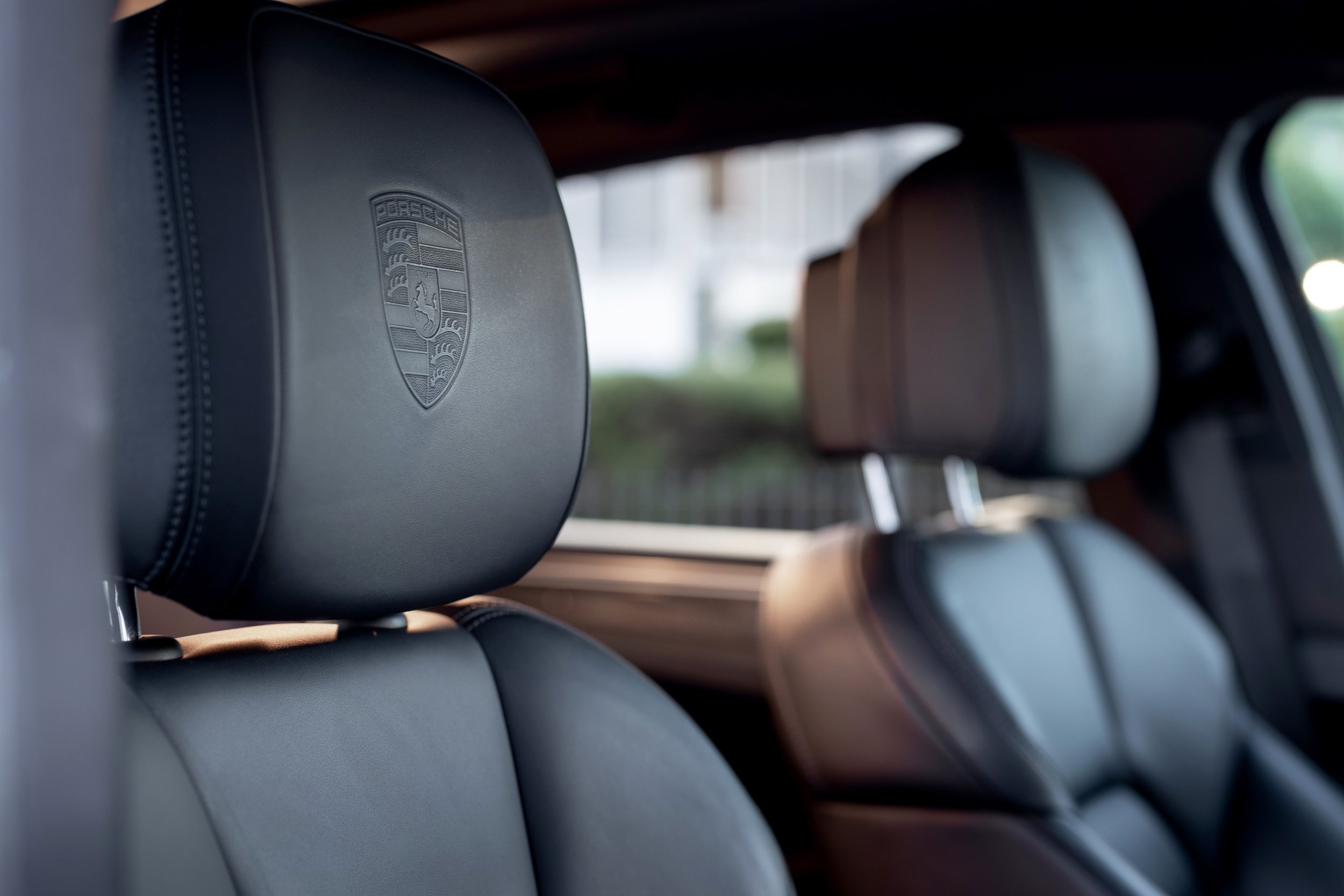 Porsche crest embossed leather headrest on 2019 Macan S sport seat, all four headrests visible in depth-of-field shot