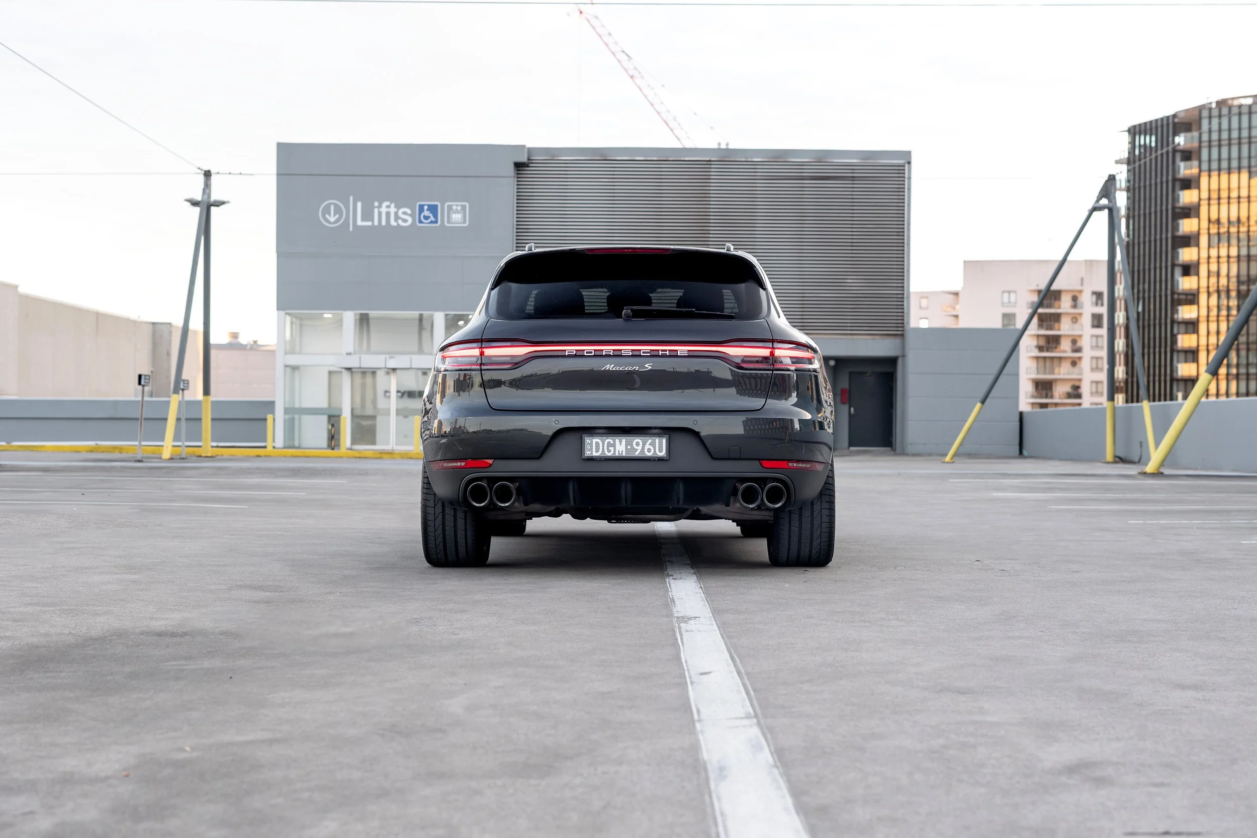 2019 Porsche Macan S rear straight-on view, full-width LED taillights and quad sports exhaust, Sydney rooftop
