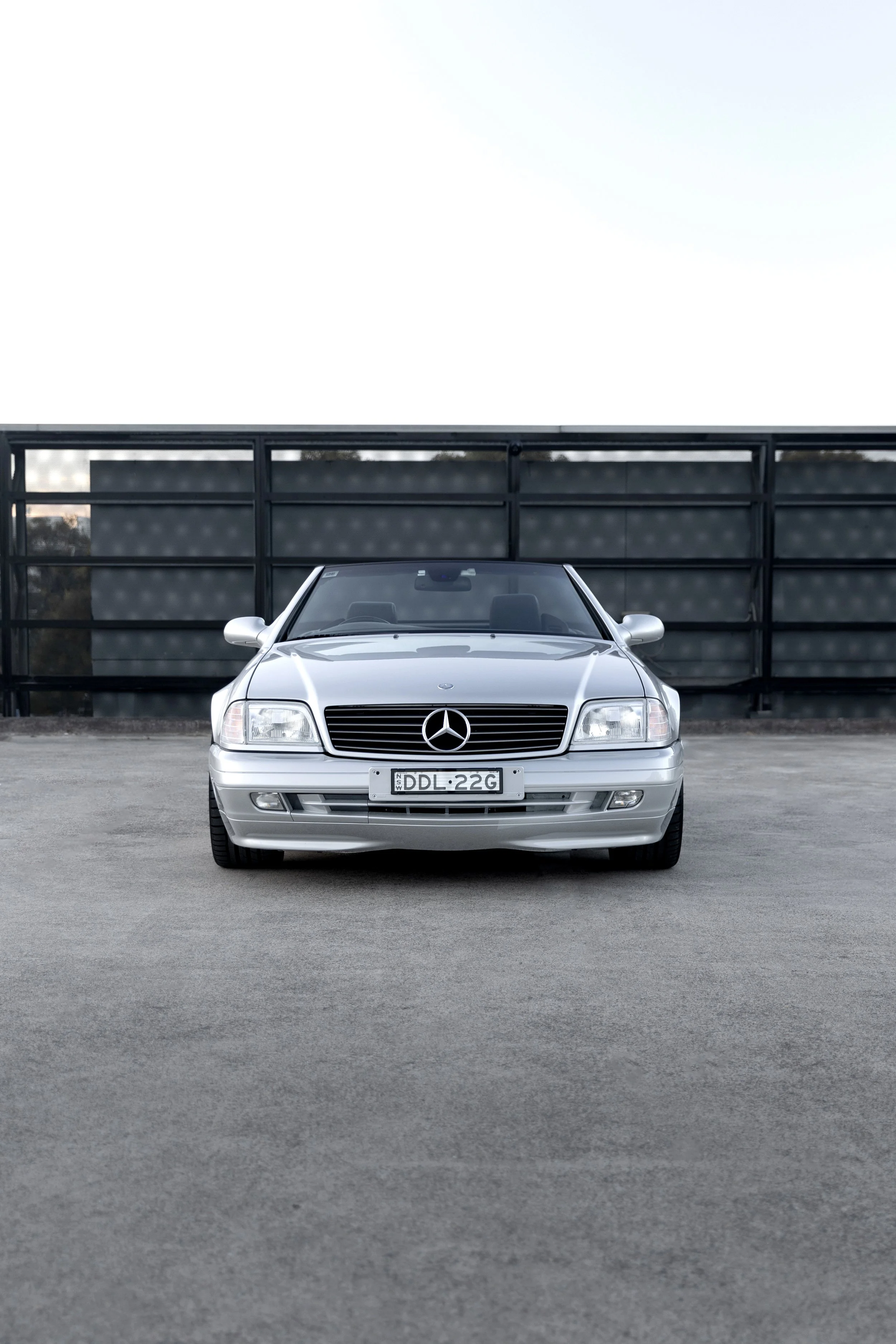 Front-end view of a silver 1999 Mercedes-Benz SL 500 R129 roadster on a Sydney rooftop.