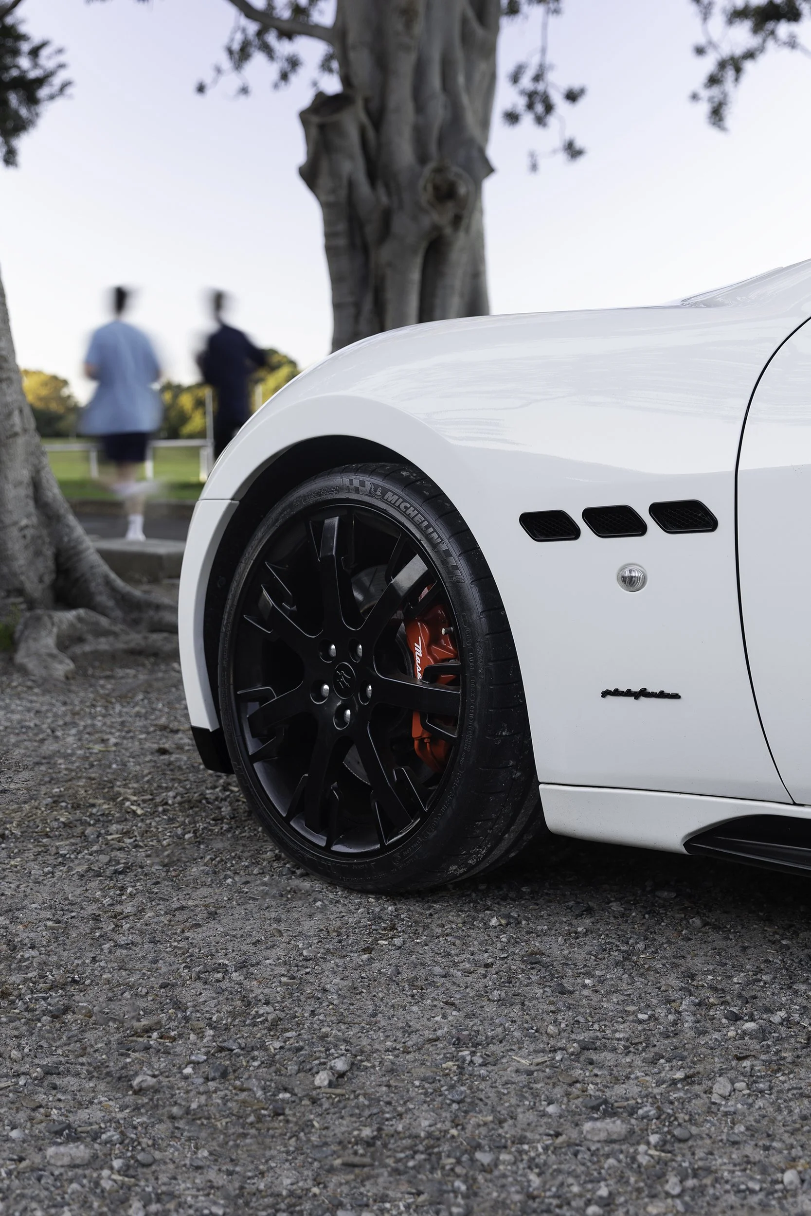 Close-up automotive photography of a Maserati's alloy wheel and red brake caliper, Sydney parkland