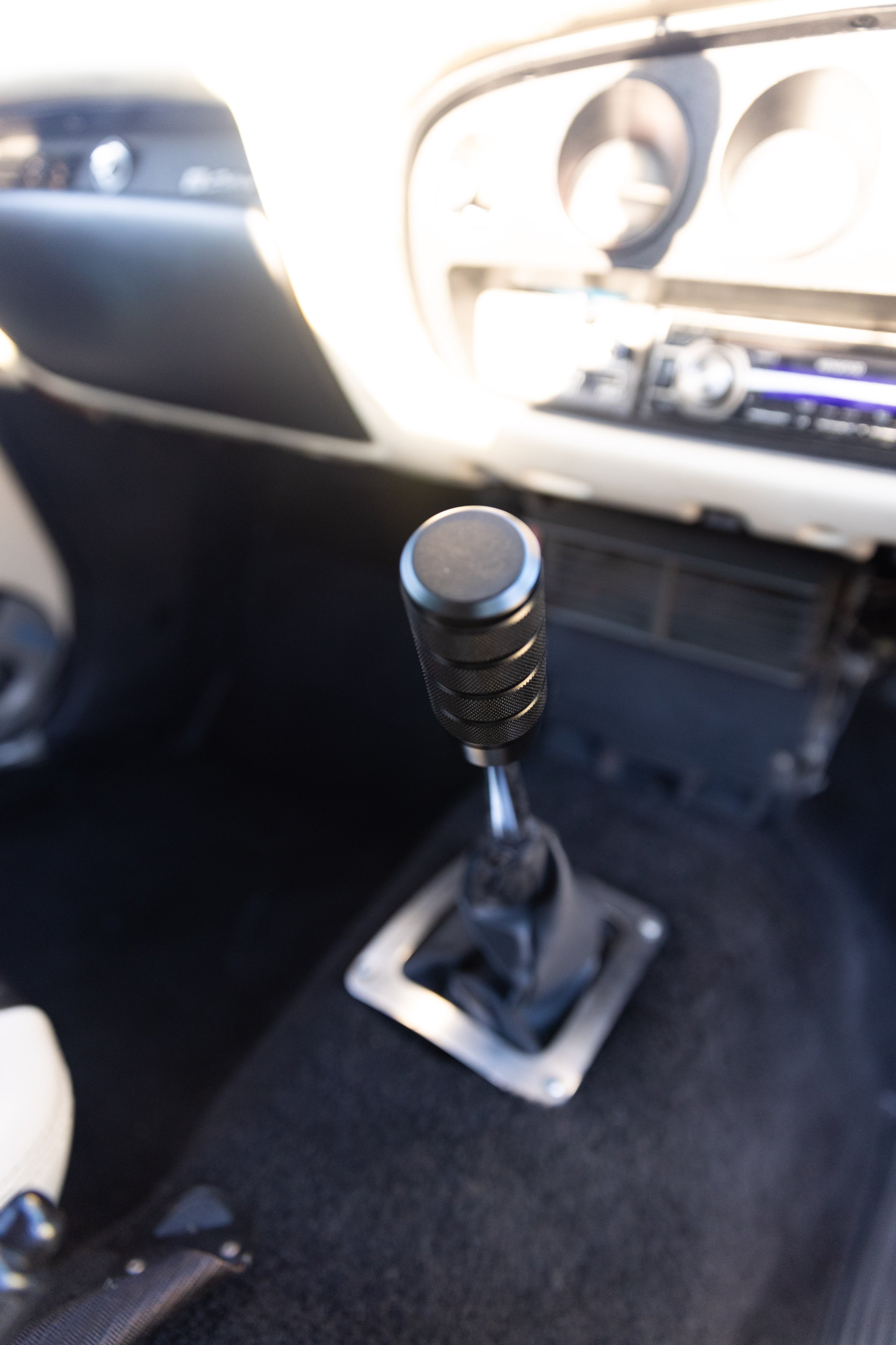 Aftermarket knurled gear shift knob in a Toyota Celica 1600GT TA22 manual transmission interior. Classic car detail photography.