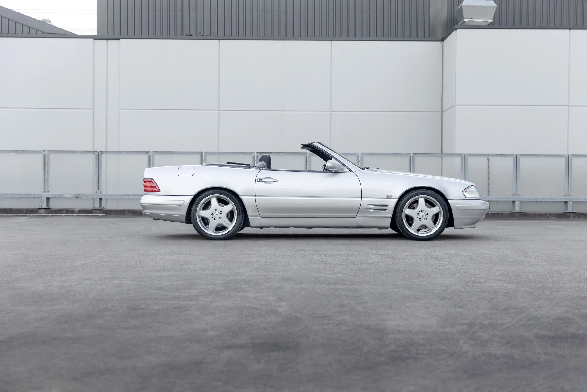 Silver 1999 Mercedes-Benz SL 500 (R129) side profile, top down against a warehouse wall, Sydney