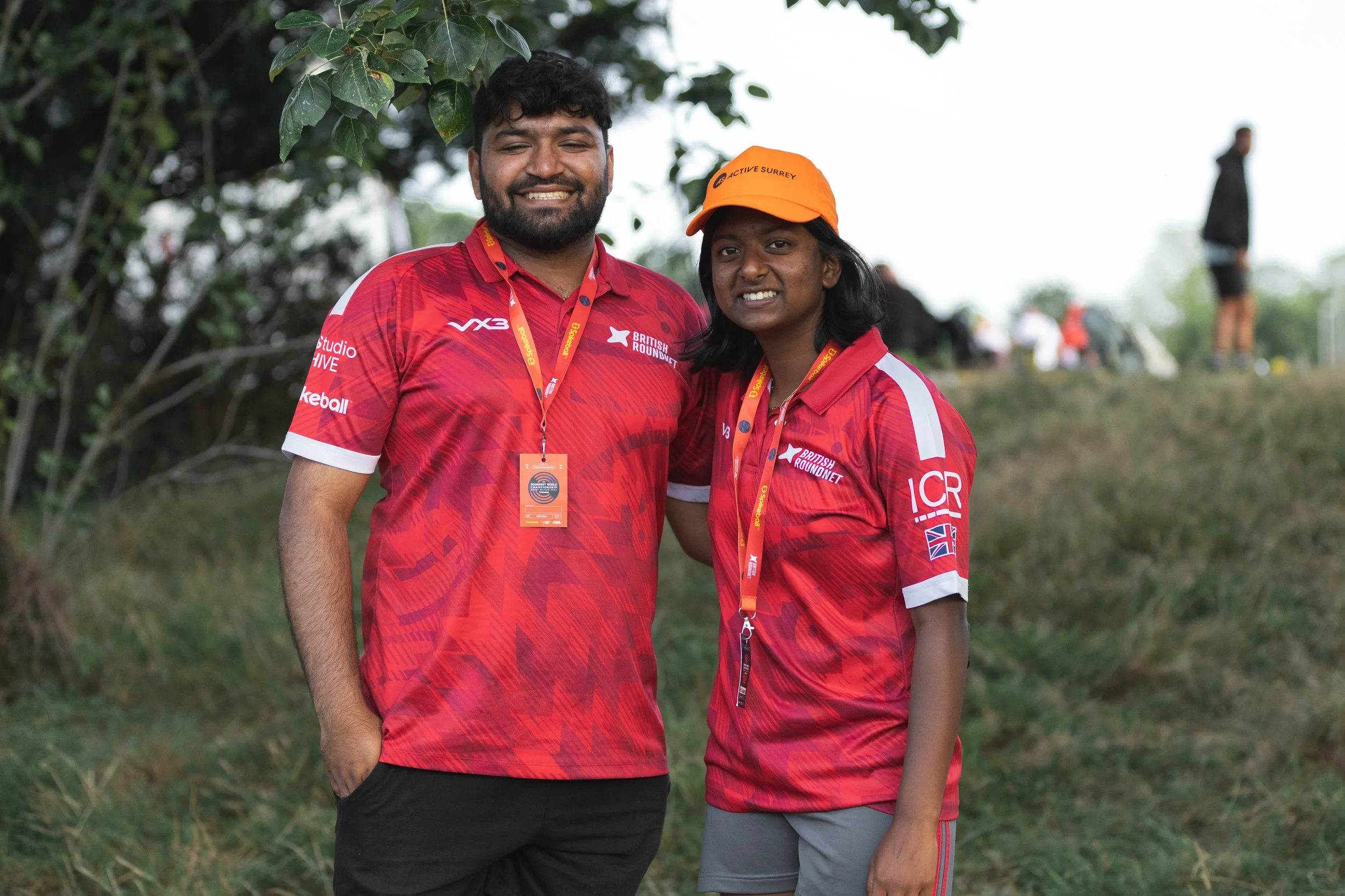 People at an outdoor event gathered around a yellow tent with 'Studio HIVE' banners. Some are handling large yellow and black spike balls, with one person inside a spike ball.