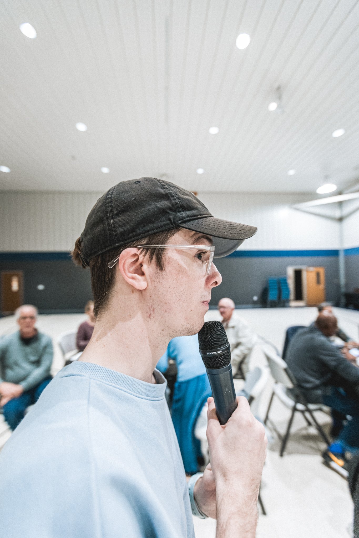 Pastor Nathan Kuenzi holding a microphone at an event.