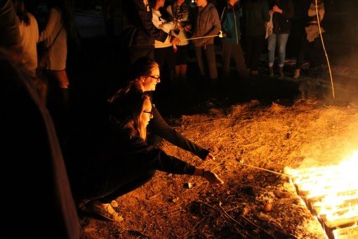 Students roast marshmallows over the fire.