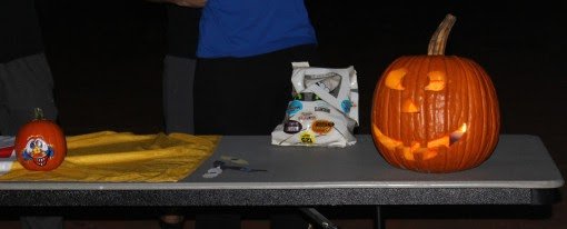 A jack-o-lantern happily keeps watch over its table.