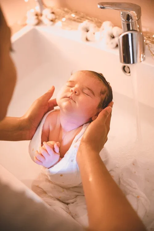 Bébé avec une doula qui lui fait un massage dans un bain Thalasso