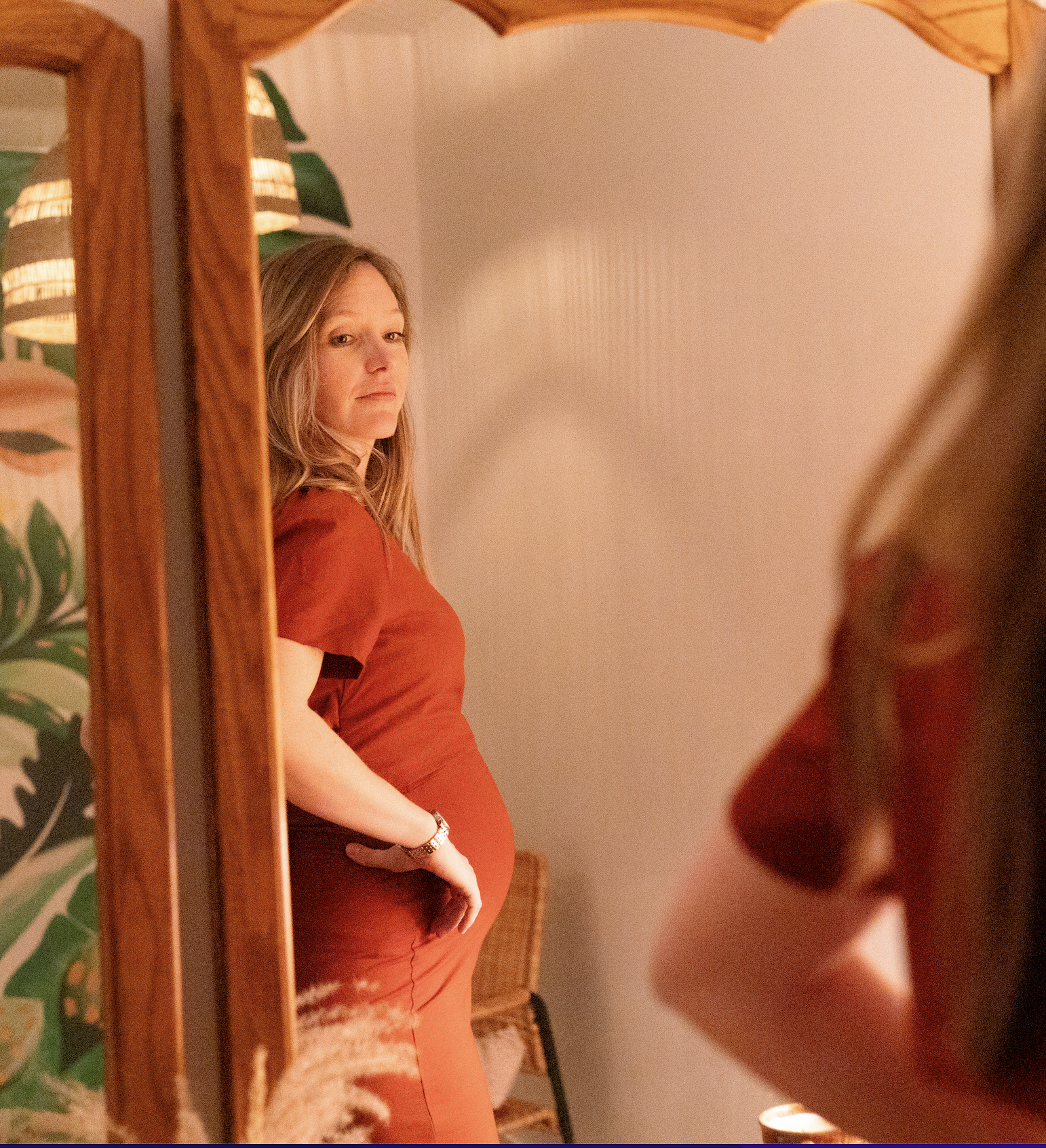 Aude, femme enceinte en robe rouge qui se regarde dans le miroire.