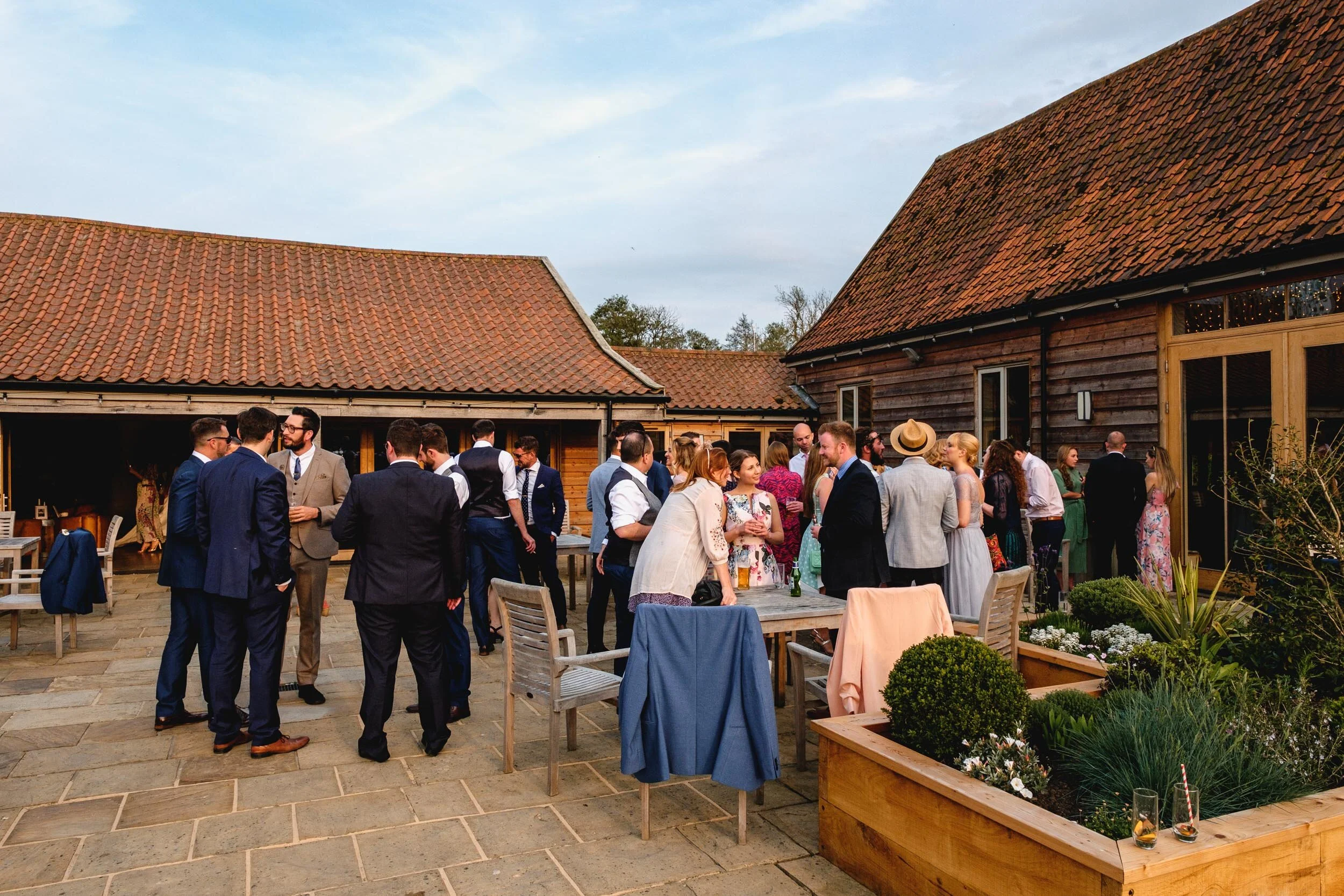 wedding guests mingling in the courtyard at easton grange lit by soft evening light