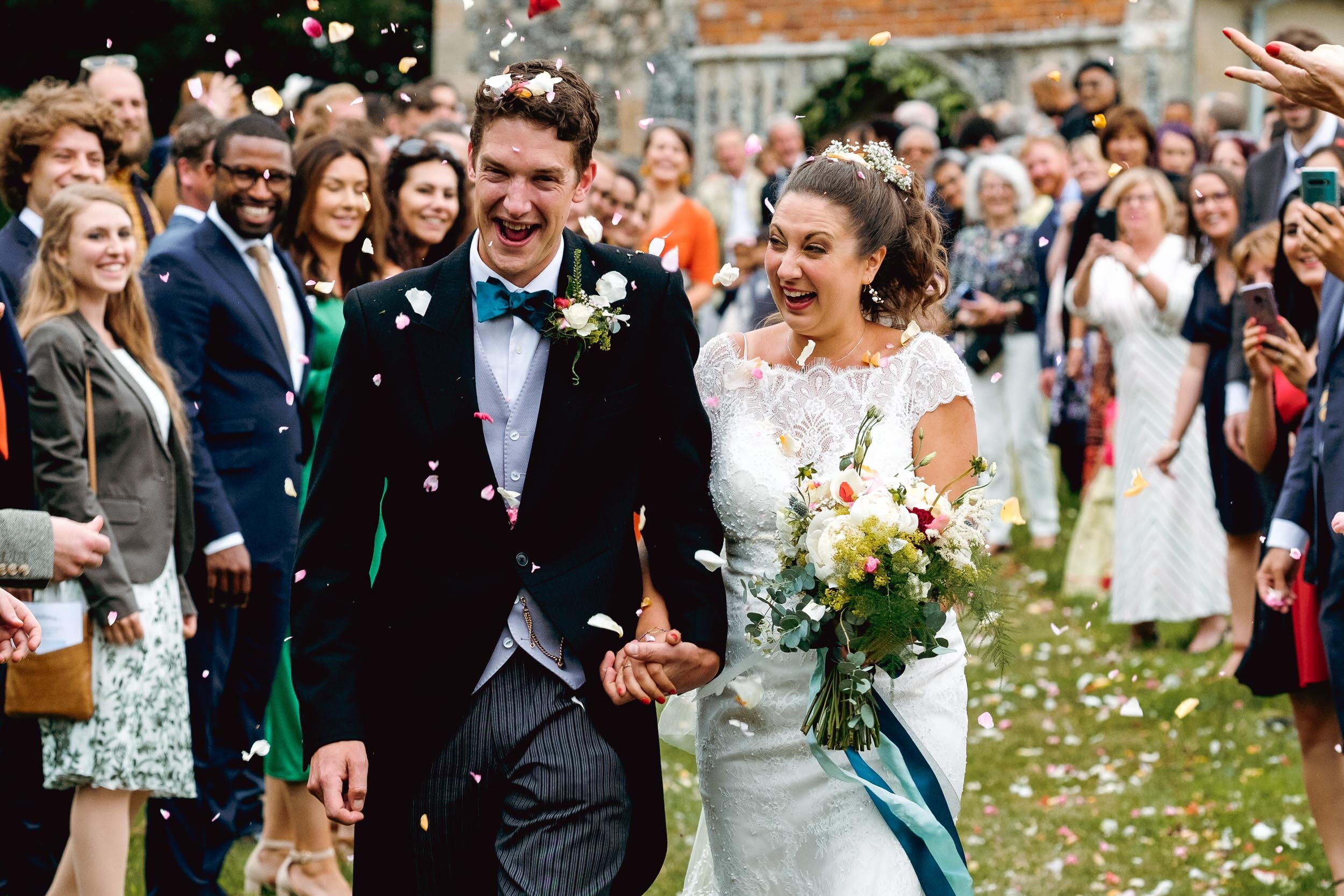 bride and groom showered with confetti at st botolphs church in iken, suffolk