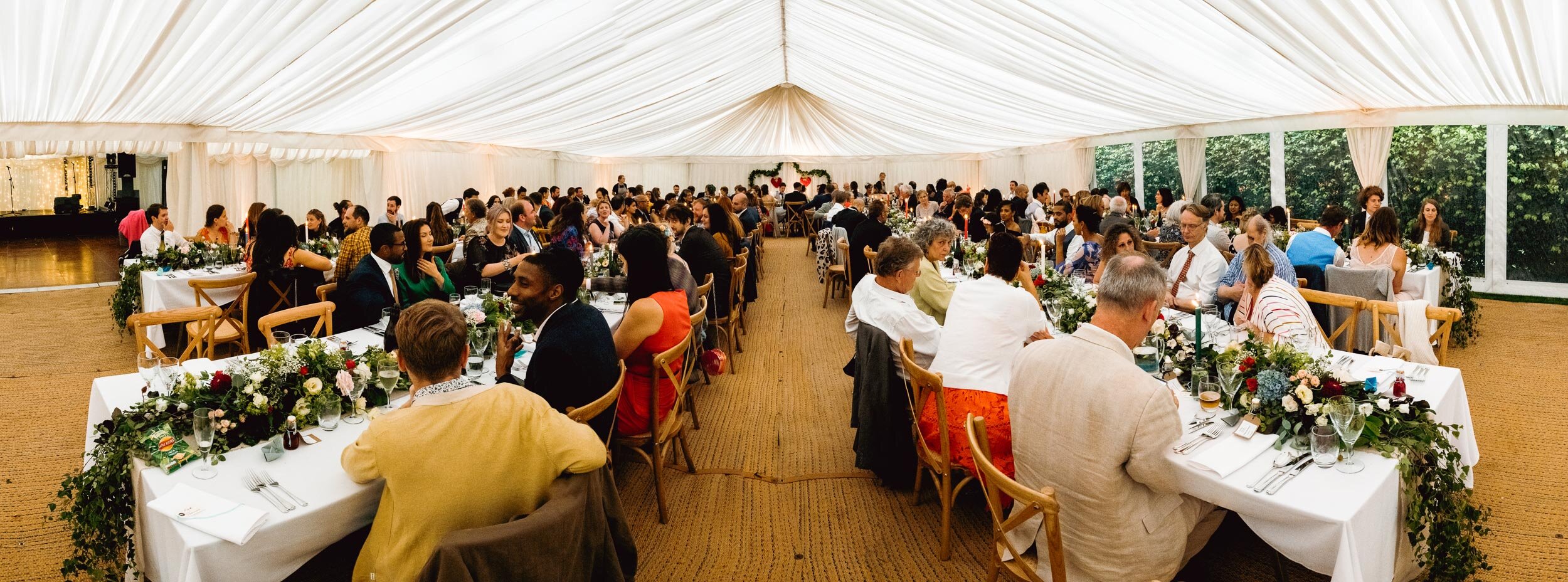 panoramic shot of interior of a marquee set up for a wedding reception with all the guests in their seats