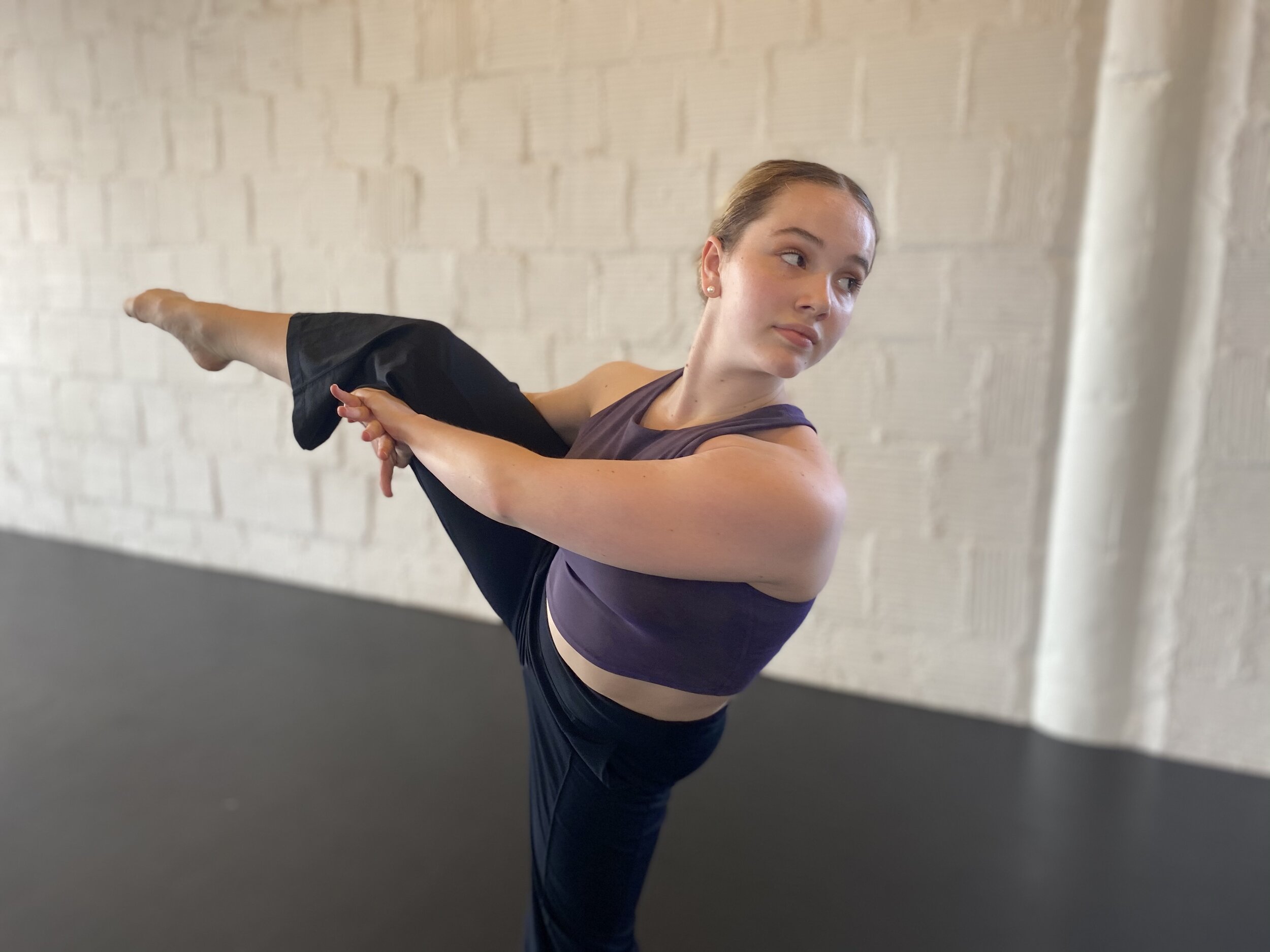 stretching moving purple top girl white brick wall Dance acting ballet jazz lyrical contemporary theater musical camp singing voice glee club Amber Keeley director Mpls classes twin cities workshops Spring Dance Theatre Academy NE Minneapolis MN St S