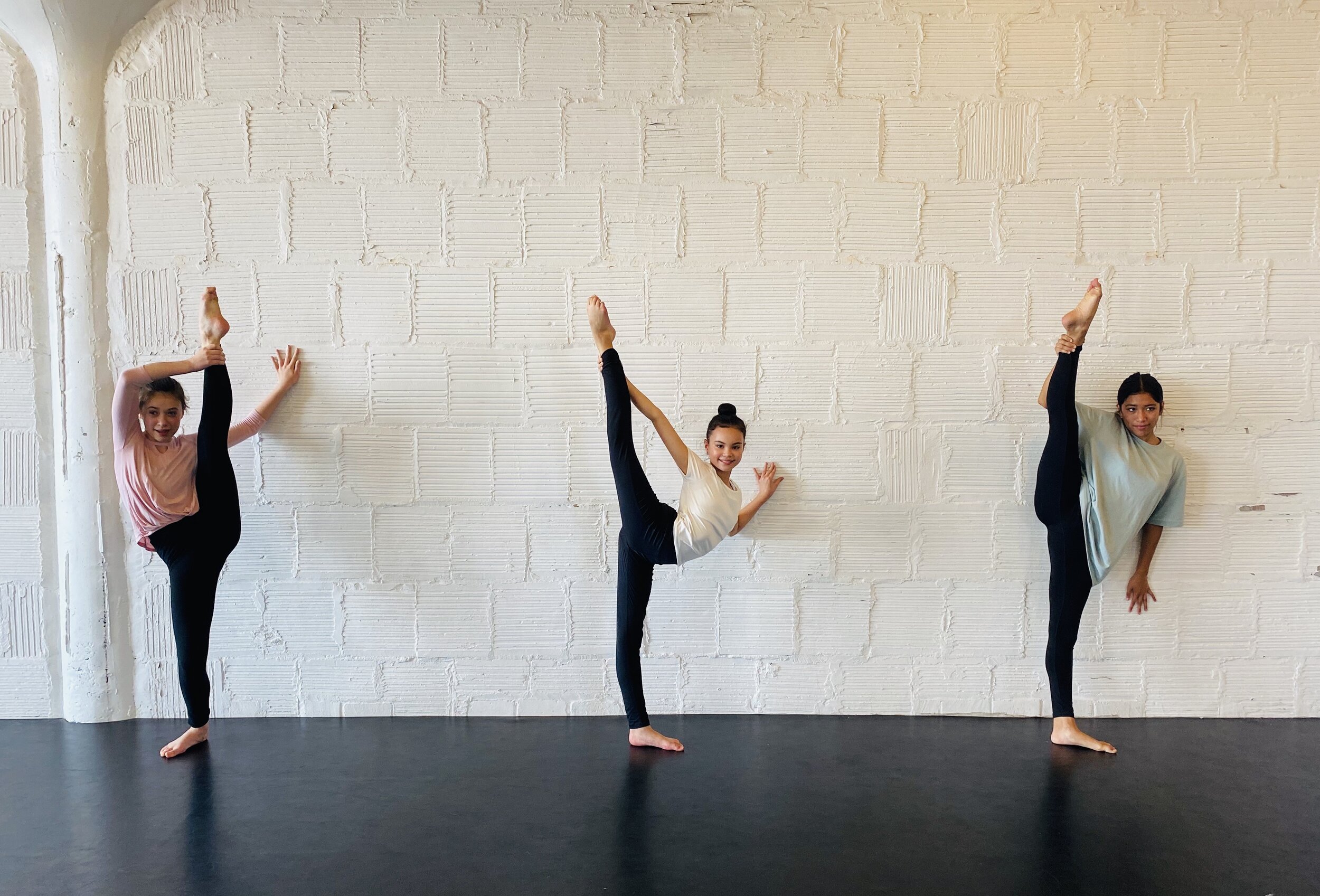 legs girls tilt hair in bun white pink teal shirts white brick wall Dance acting ballet jazz lyrical contemporary theater musical camp singing voice glee club Amber Keeley director Mpls classes twin cities workshops Spring Dance Theatre Academy NE Mi