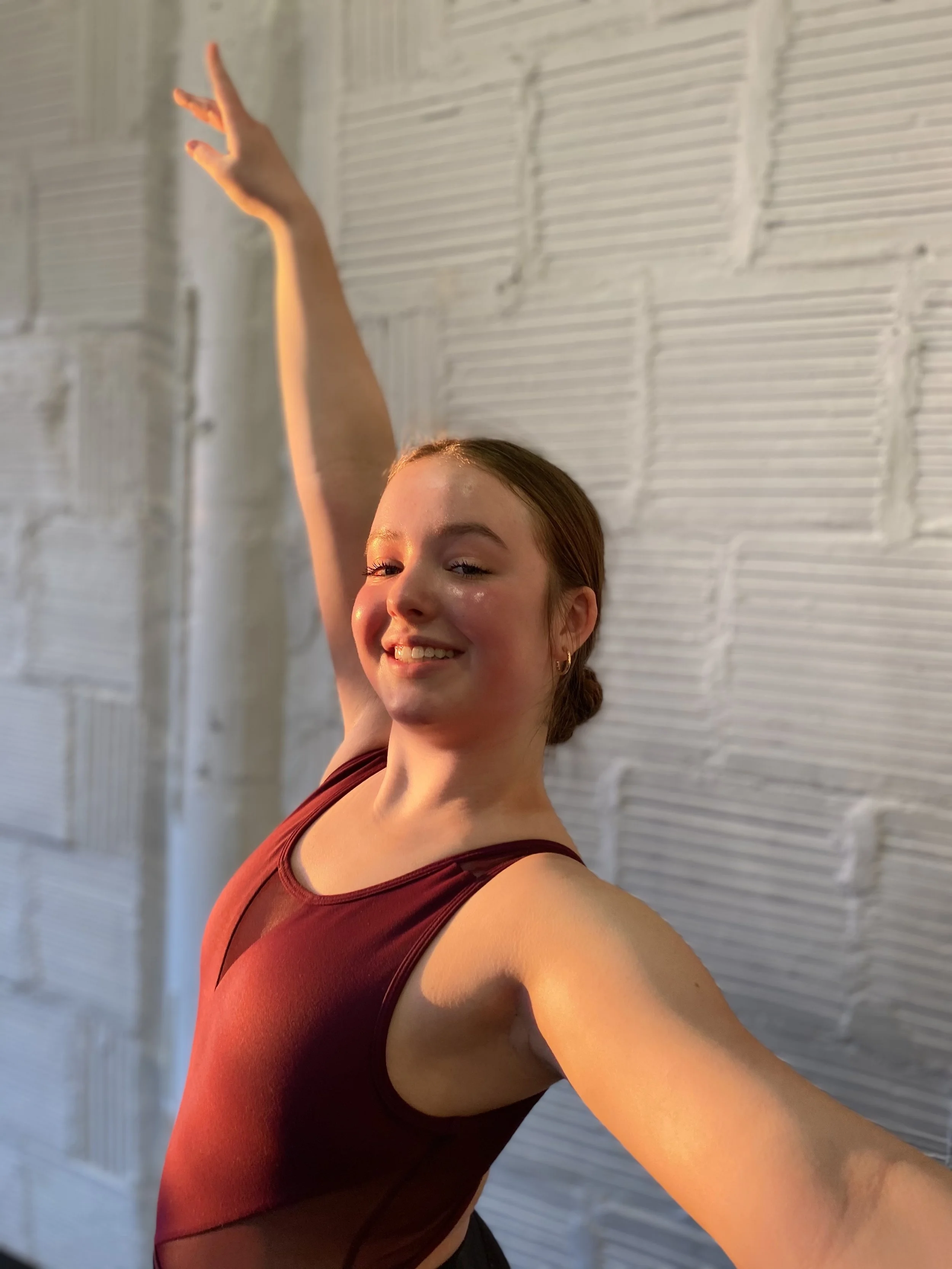 golden hour white brick wall red leotard smile arm up Dance dancer studio acting ballet jazz lyrical contemporary theater musical camp singing voice glee club Amber Keeley director Mpls classes twin cities workshops Spring Dance Theatre Academy NE Mi