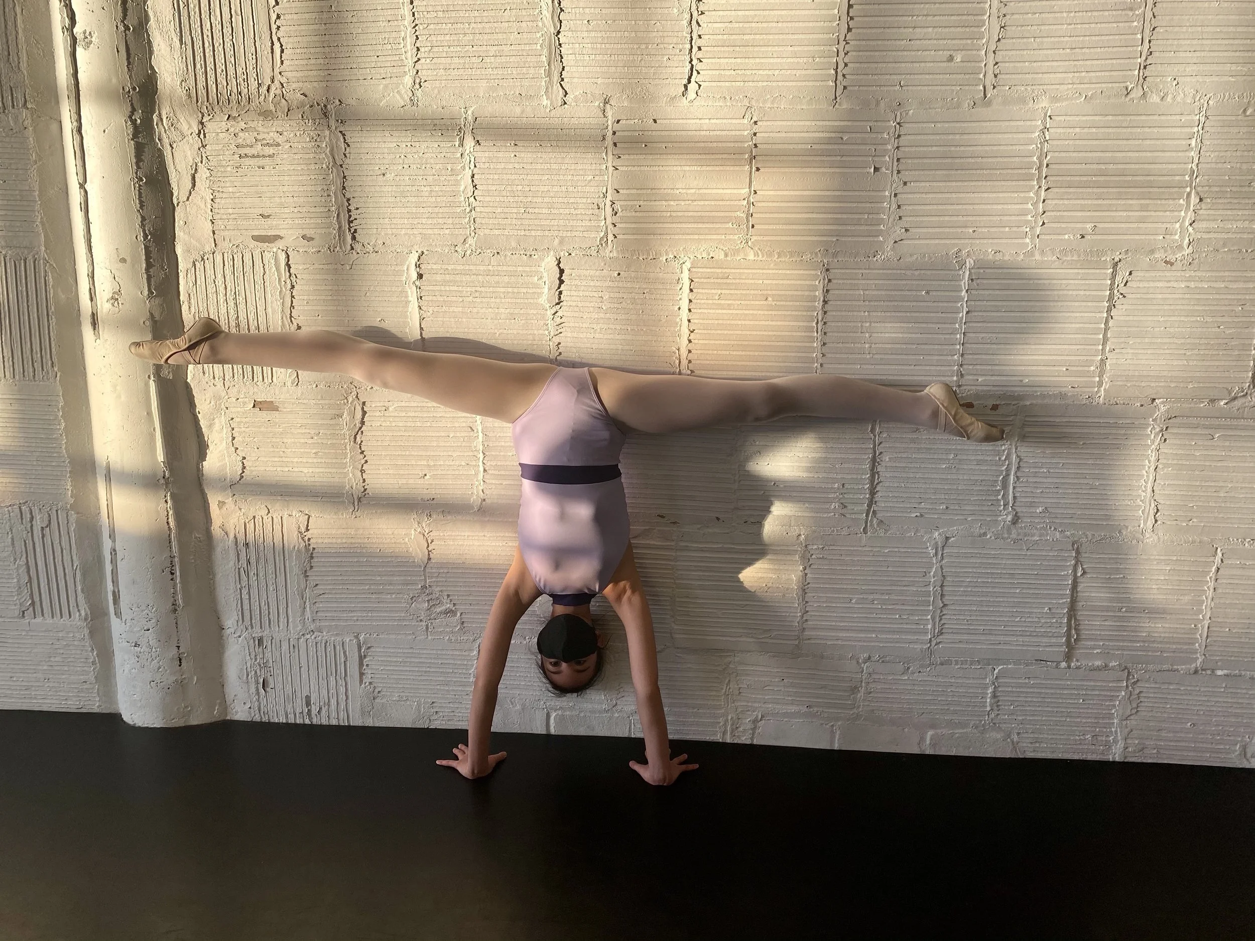 window shadow handstand split straddle purple leotard white brick wall Dance dancer studio acting ballet jazz lyrical contemporary theater musical camp singing voice glee club Amber Keeley director Mpls classes twin cities workshops Spring Dance Thea