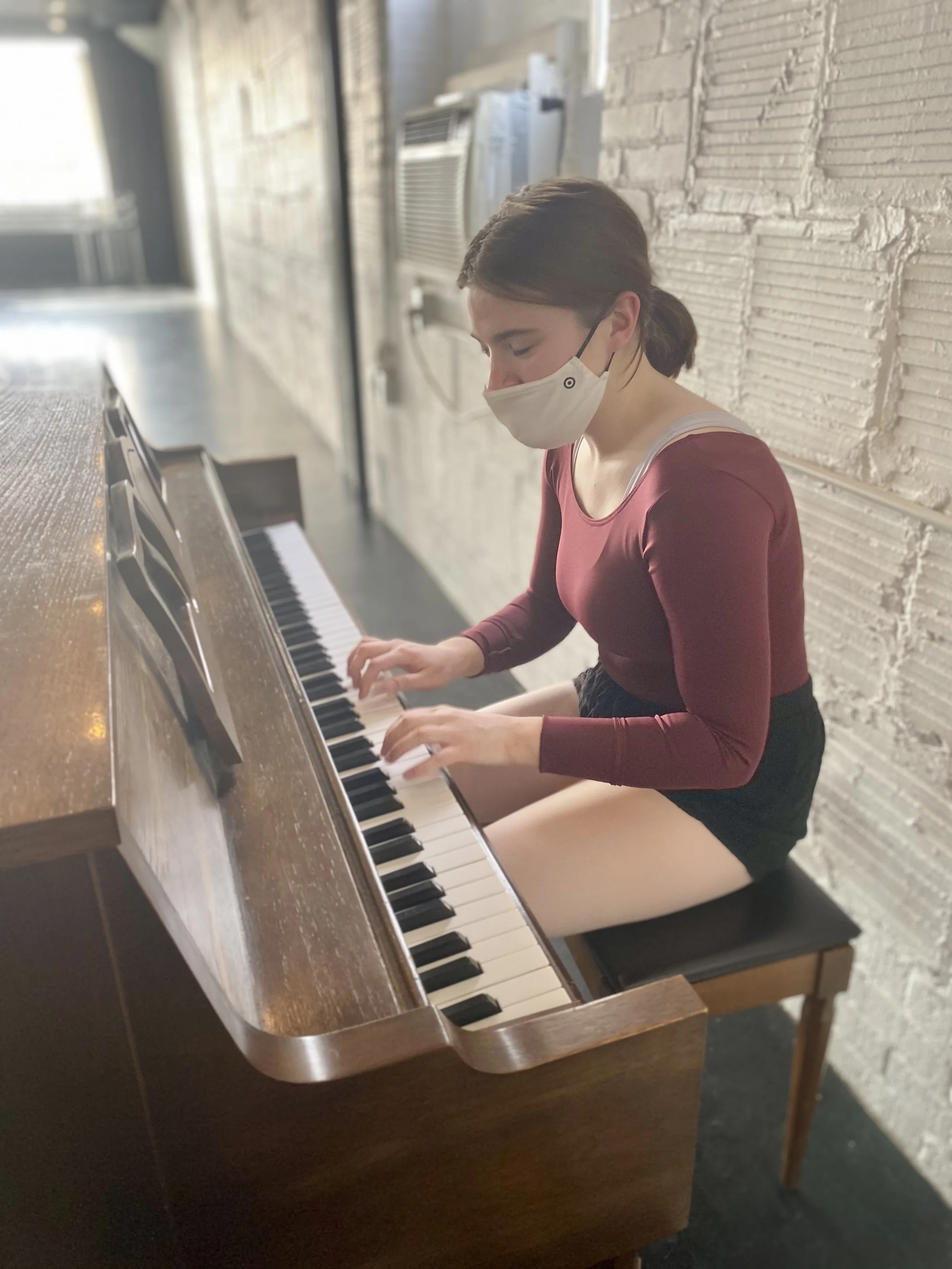 brown piano maroon leotard singing playing white brick wall Dance dancer studio acting ballet jazz lyrical contemporary theater musical camp singing voice glee club Amber Keeley director Mpls classes twin cities workshops Spring Dance Theatre Academy