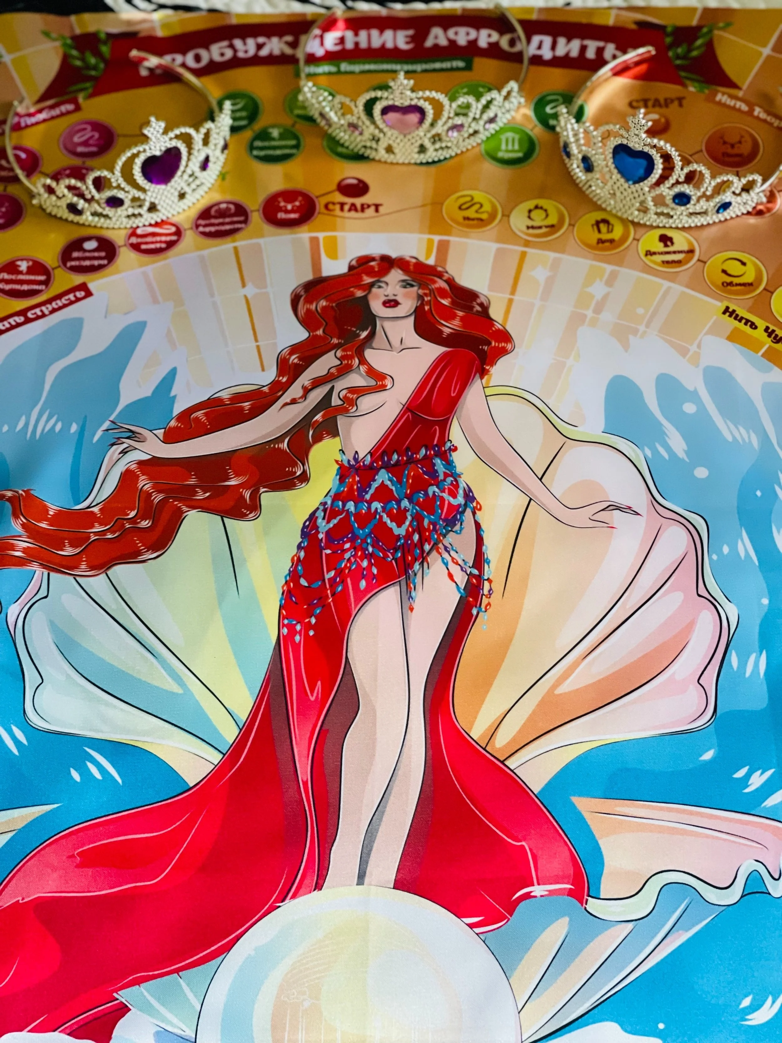 An illustrated scene from a board game featuring a woman with long red hair wearing a red dress, surrounded by colorful game elements, including three tiaras with purple, blue, and pink jewels, and various game tokens and paths.