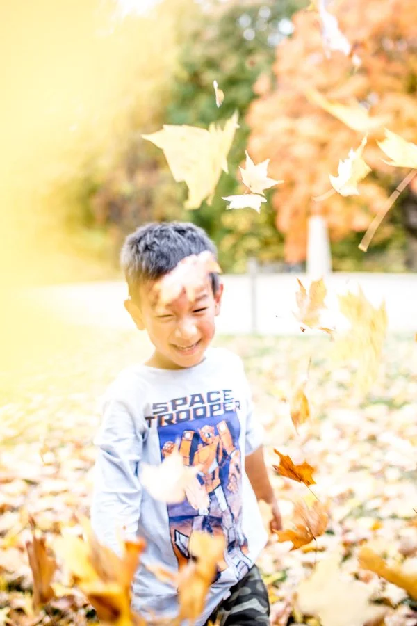 Joyful child playing in leaves