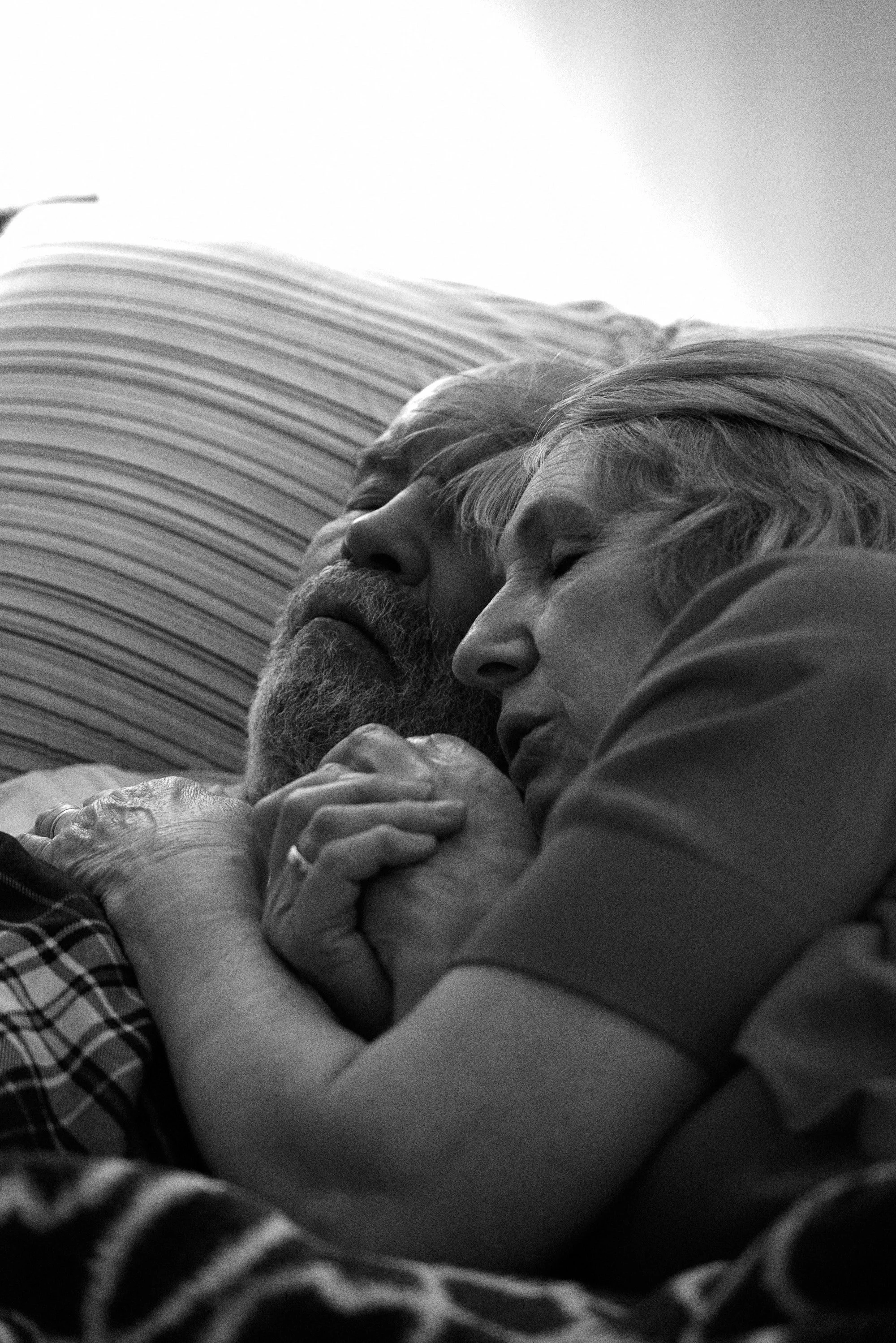 Elderly couple sleeping together, holding hands in a peaceful embrace.